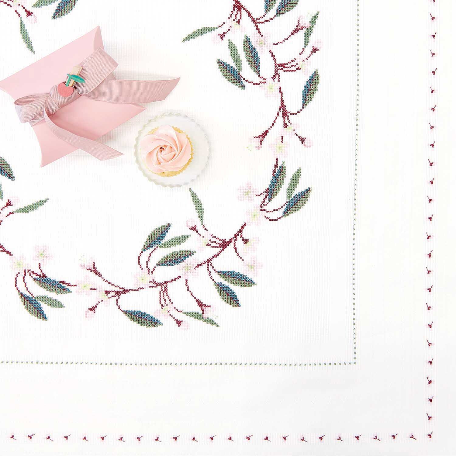 Stickanleitung Tischdecke mit Kirschzweigen: Weiße Tischdecke mit gestickten Kirschzweigen, rosa Schleife und Blume.