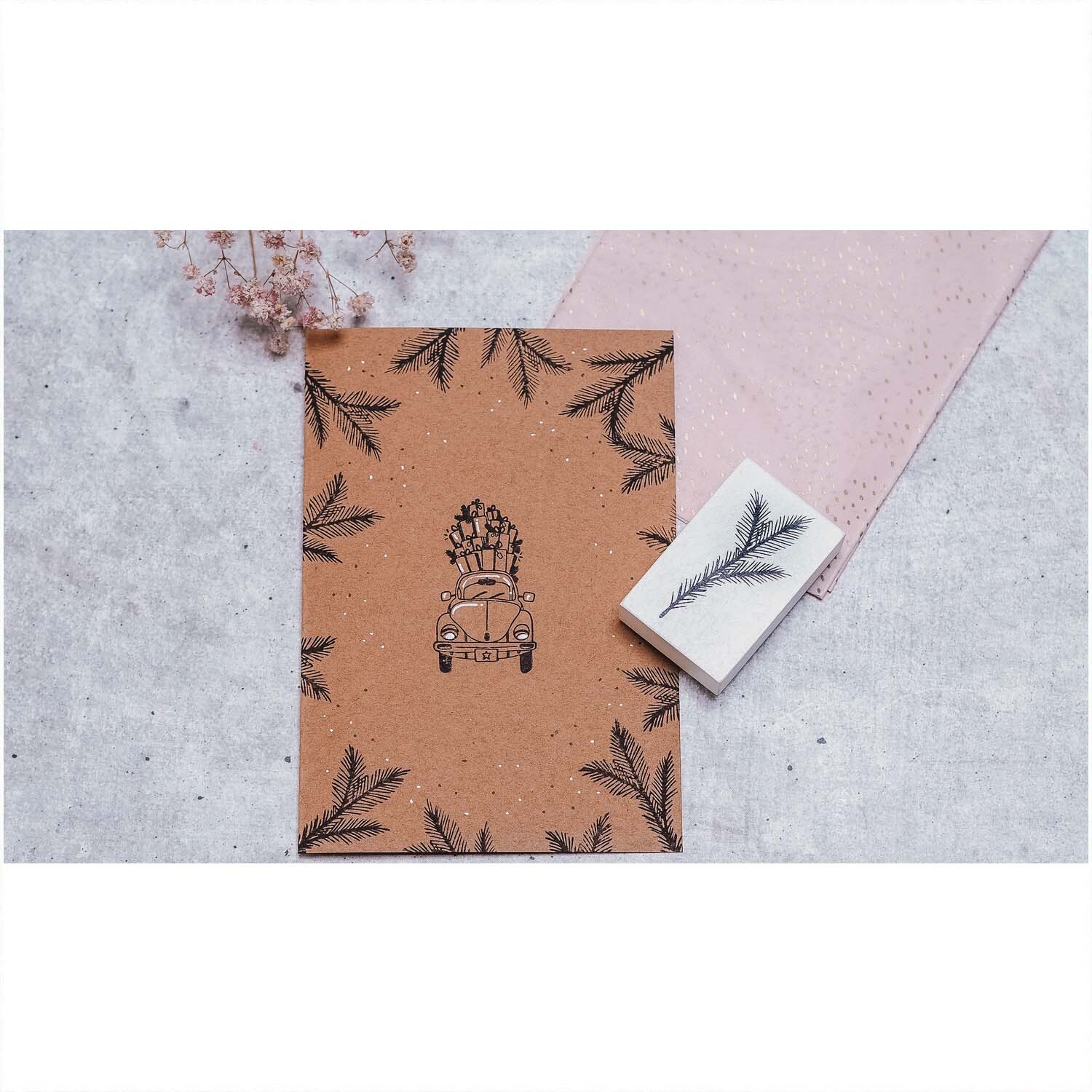 Stempel Tannenzweig weiß 35x55mm von May&Berry auf einem Notizbuch mit Tannenzweig-Muster.