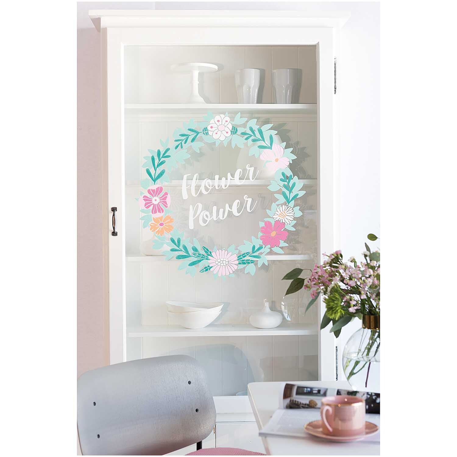 Vorlagenmappe Flowers and Plants: Ein weißer Schrank mit Blumenkranz und Schriftzug "Flower Power" auf der Glastür, dekoriert mit Geschirr.