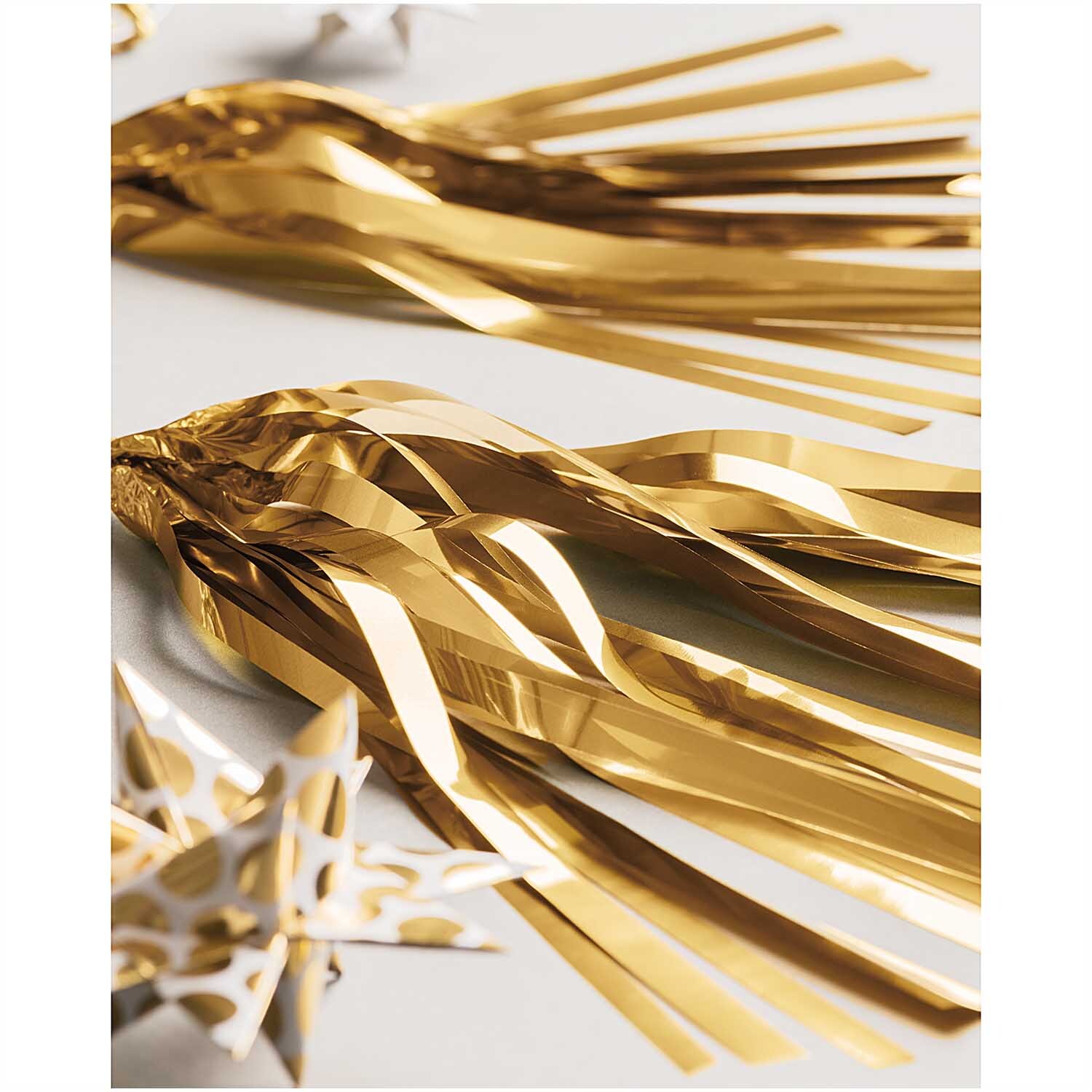 Paper Poetry Girlande Quasten in glänzendem Gold von Rico Design, dekorativ arrangiert auf einem Tisch. Ideal für festliche Anlässe.