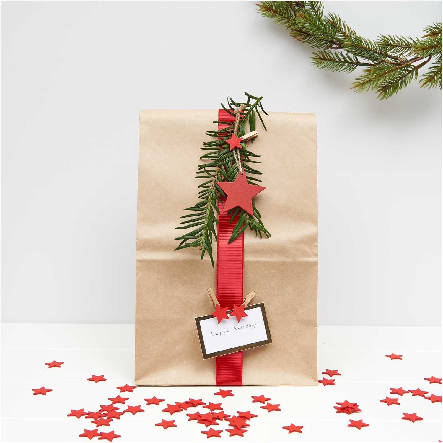 Dekoklammern Stern rot 3cm 8 Stück von Rico Design an einem Geschenk mit Tannenzweig und Karte.