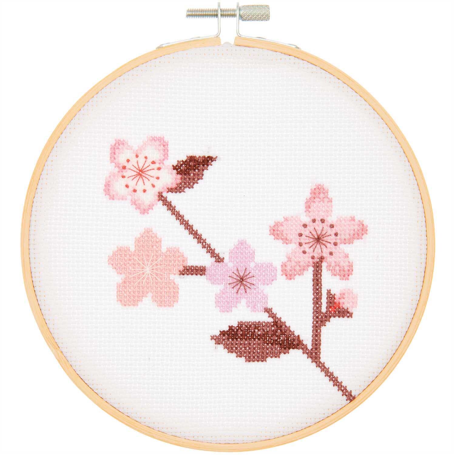 Stickpackung Kirschzweig Bild Ø 15cm zeigt zarte rosa Kirschblüten auf weißem Stoff, präsentiert von Rico Design.
