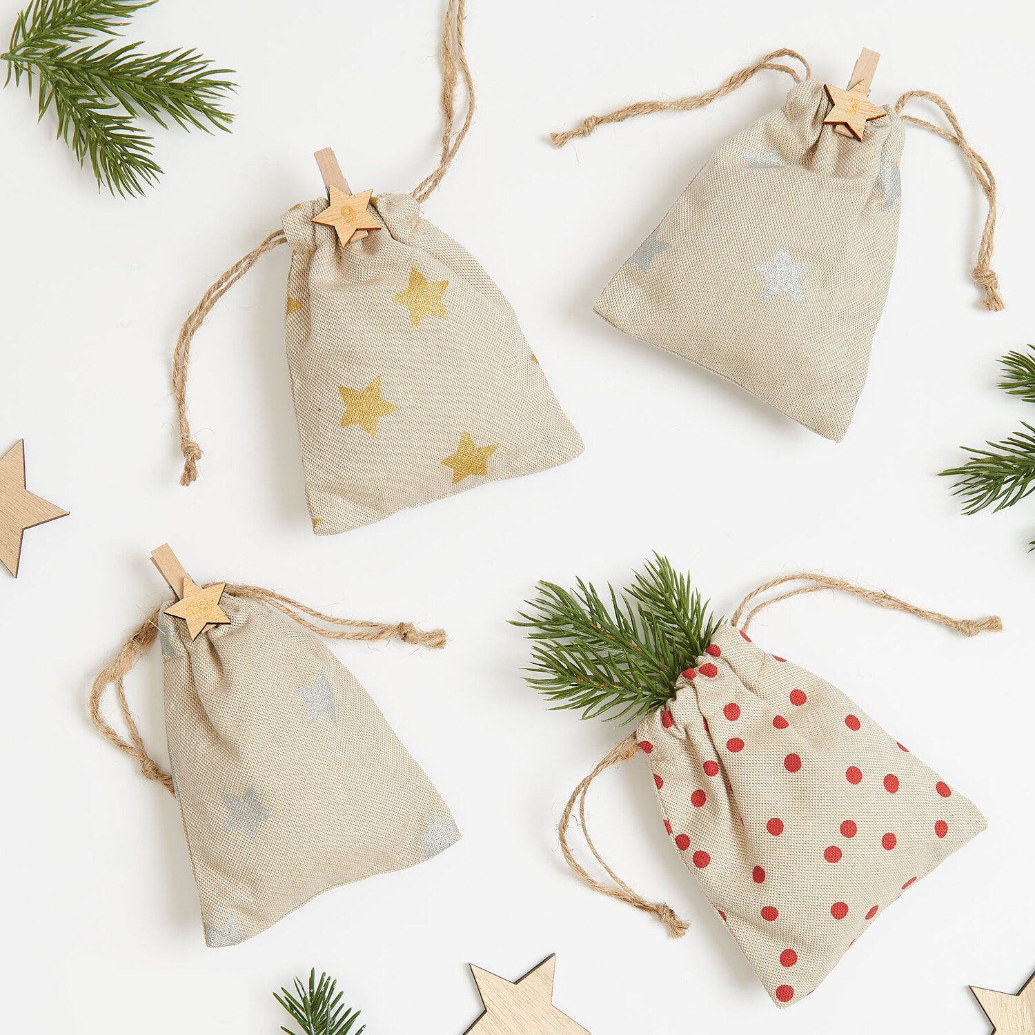Nähanleitung Adventskalender-Säckchen: Vier dekorative Stoffbeutel mit Stern- und Punktmustern, ideal für weihnachtliche Dekorationen.