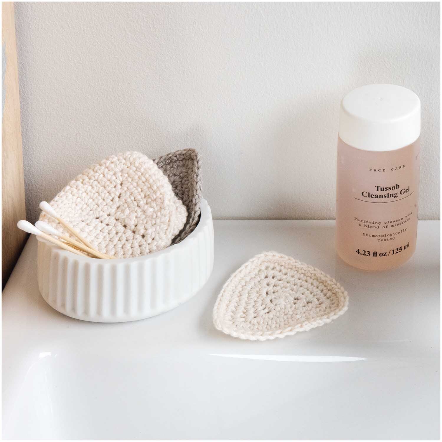 Creative Cotton dk: Handgemachte, cremefarbene Reinigungspads neben Tussah Cleansing Gel auf weißem Tisch.