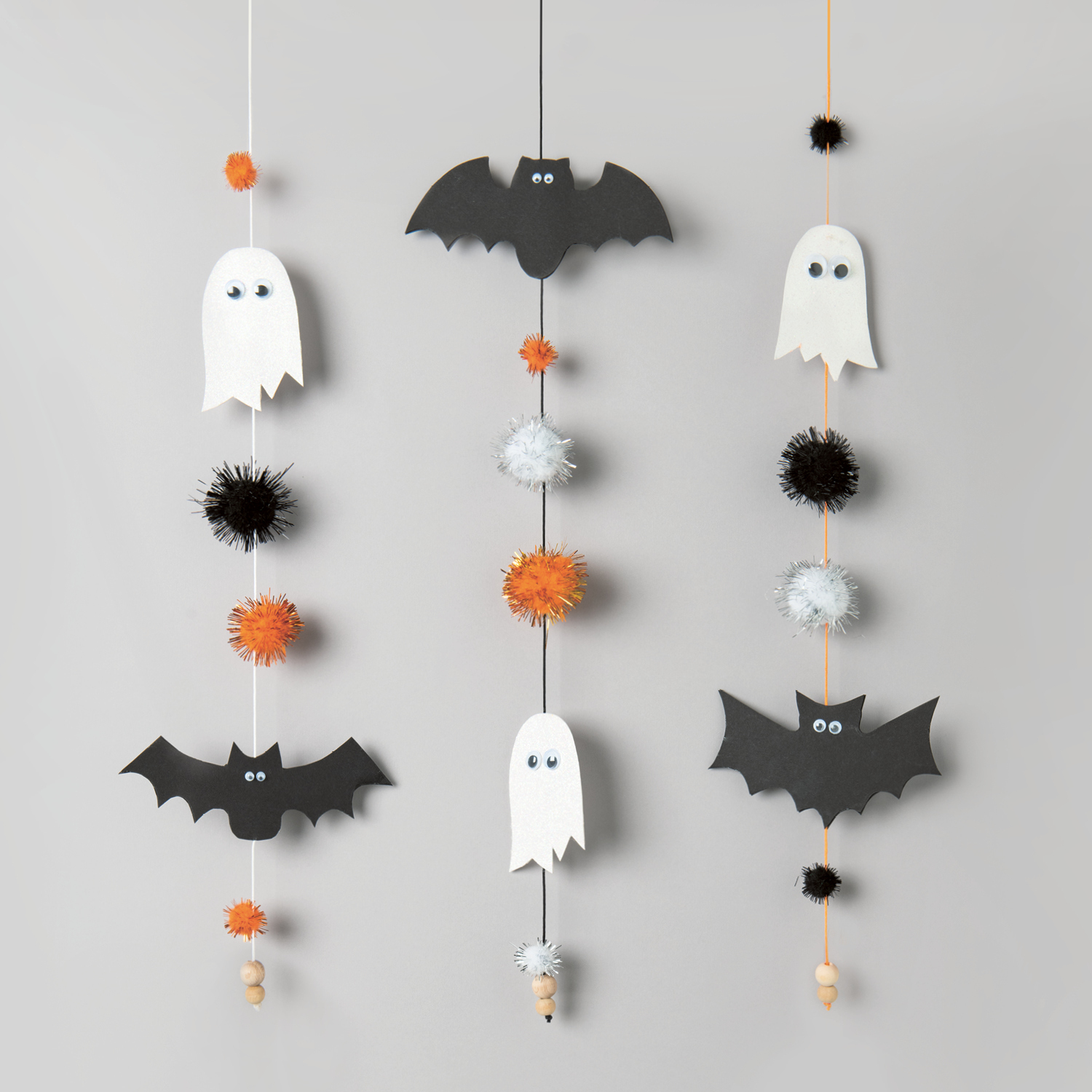 Bastelanleitung Halloween-Girlande mit schwarzen Fledermäusen, weißen Geistern und bunten Pompons.