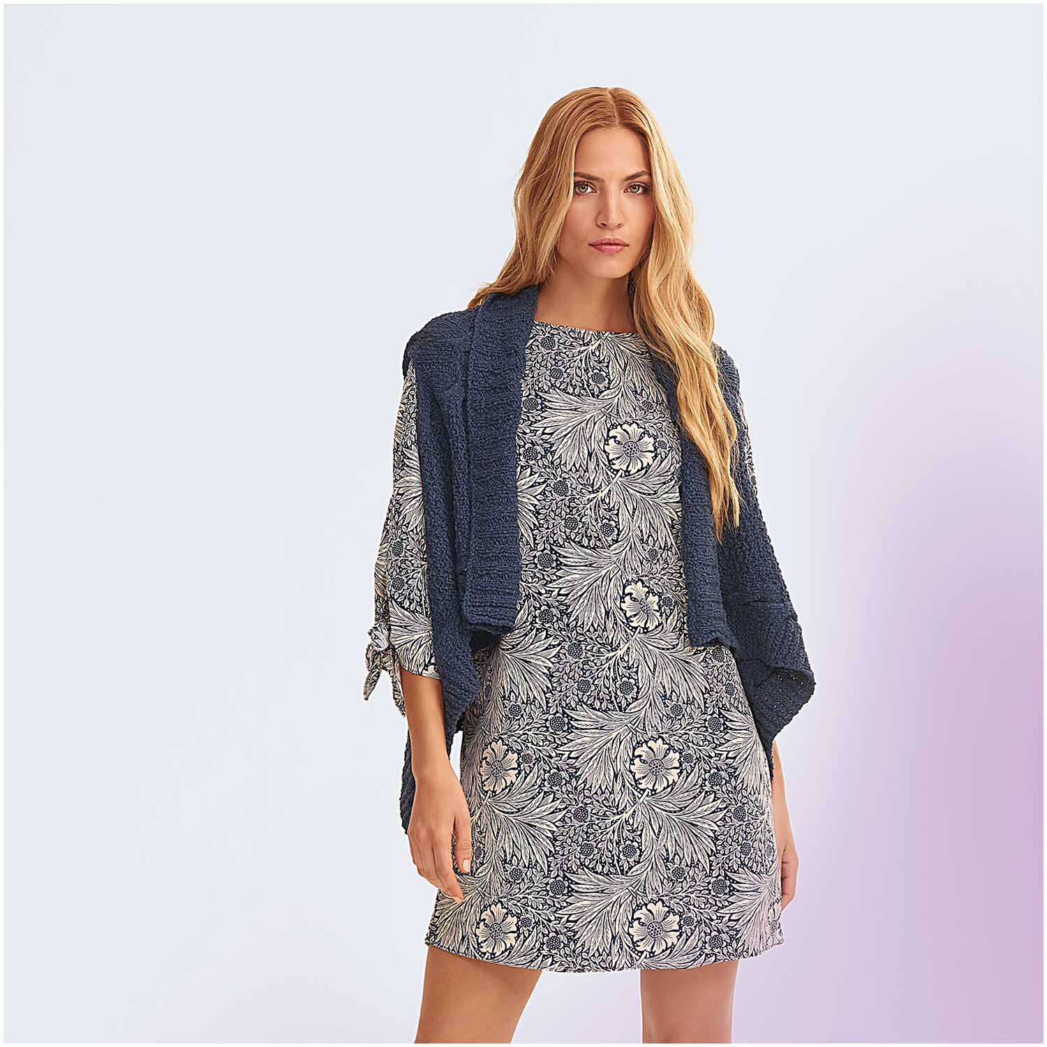 Fashion Linen Swell aran: Frau trägt ein marineblaues Strickoberteil von Rico Design über einem gemusterten Kleid.