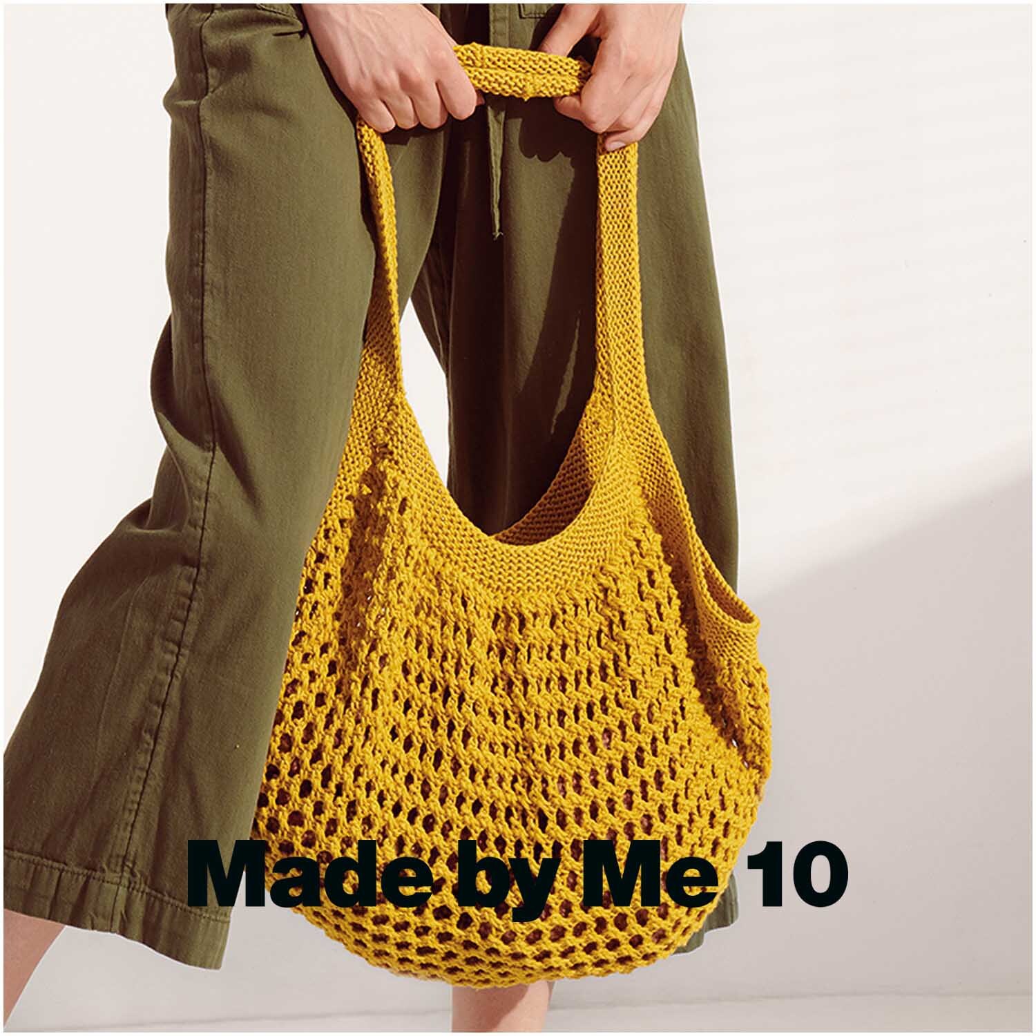 Creative Cotton aran: Handgefertigte Tasche in Senf, getragen von Person in grüner Hose. Perfekt für den Sommer.
