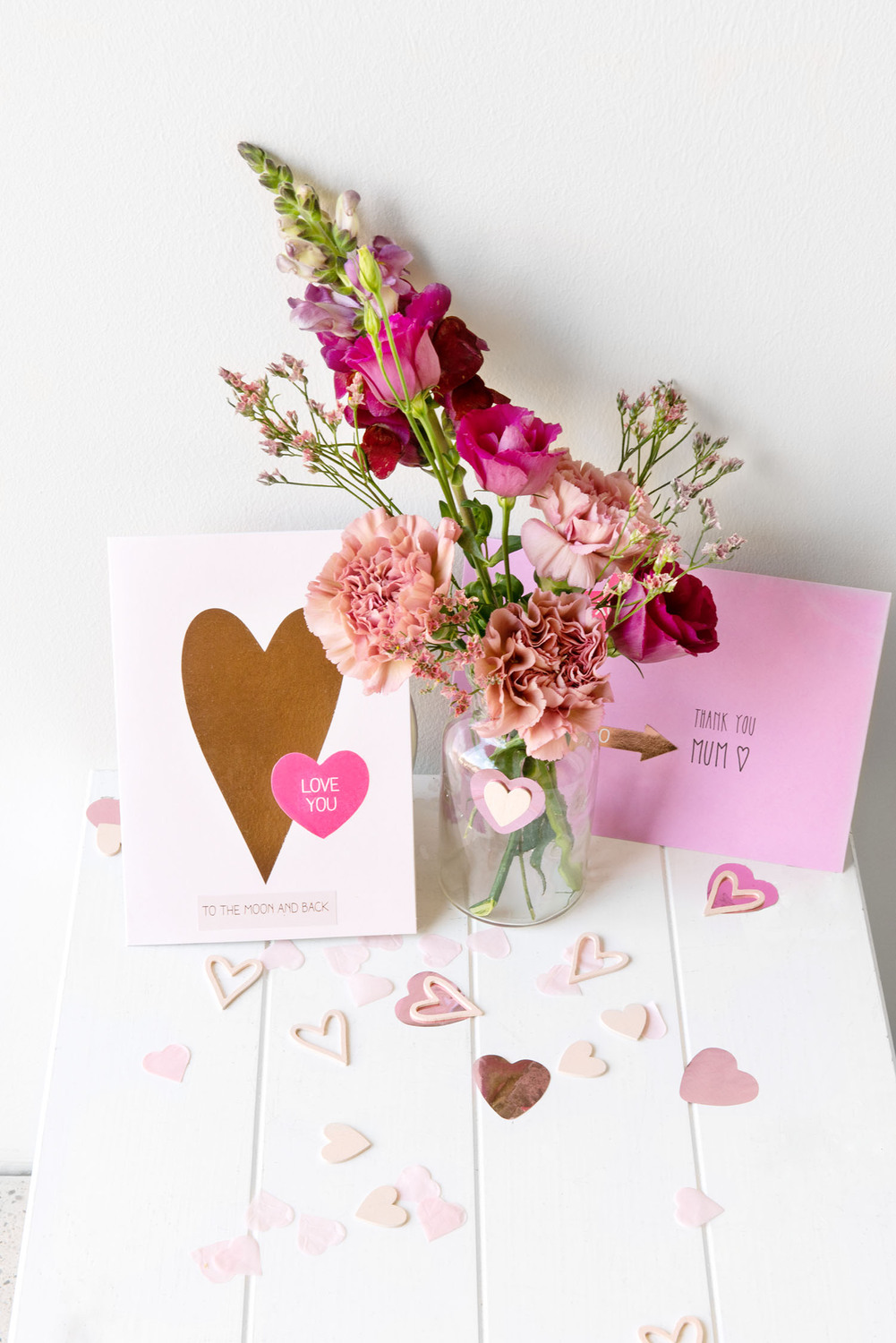 Paper Poetry Grußkartenset mit Herzmotiv in Pink, neben einem Blumenstrauß auf weißem Tisch arrangiert.