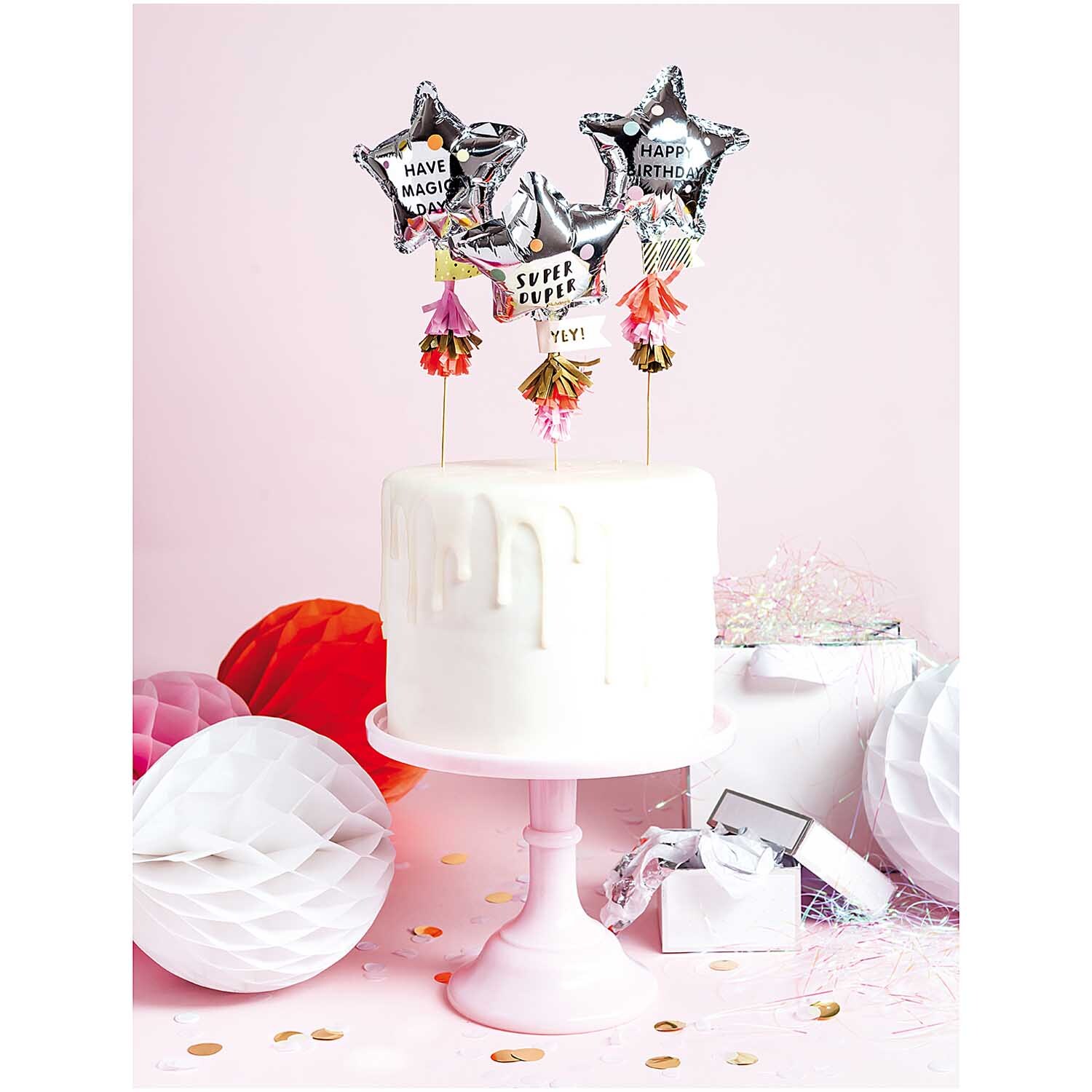 Kuchentopper Folienballon-Sterne 3 Stück auf weißem Kuchen, umgeben von Partydekorationen.