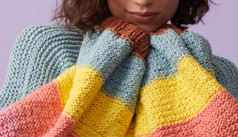 Strickanleitung Jacke aus Creative So Cool & So Soft Print: Frau trägt bunte gestrickte Jacke in Pastelltönen, Nahaufnahme des weichen Strickmusters.