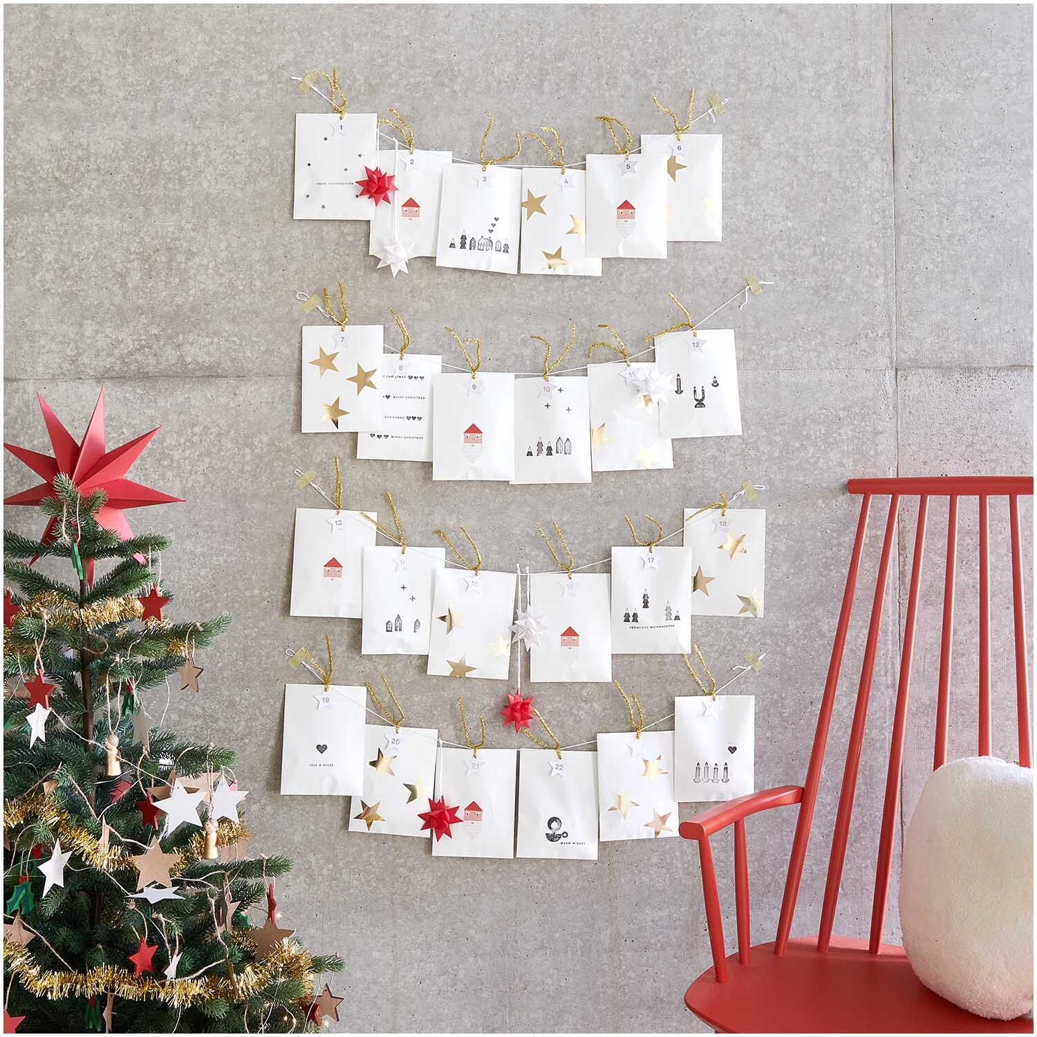 Paper Poetry Sticker Sterne 5cm 120 Stück auf der Rolle Hot Foil, dekoriert an einer Wand neben einem Weihnachtsbaum und einem roten Stuhl.