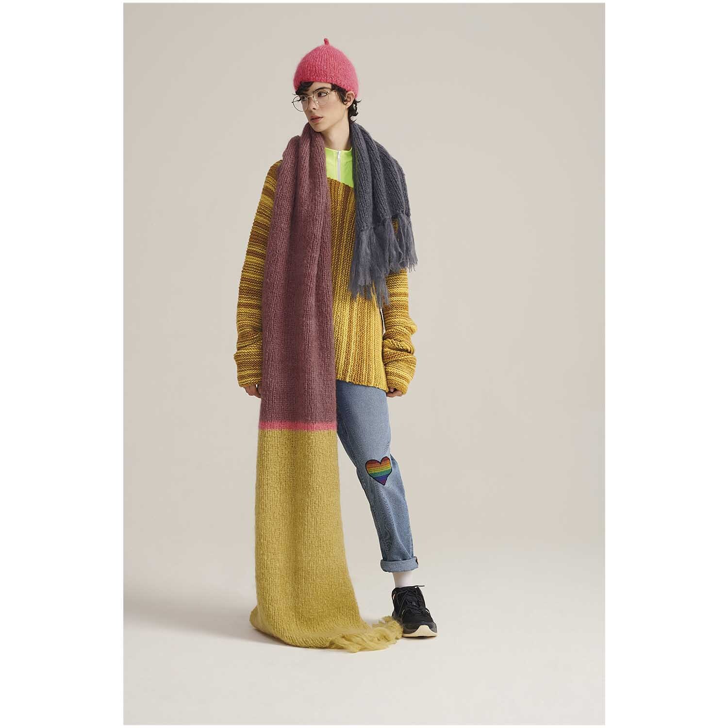 Fashion Mohair Merino Chunky: Person trägt langen, bunten Schal und gelben Pullover, kombiniert mit Jeans und Mütze.