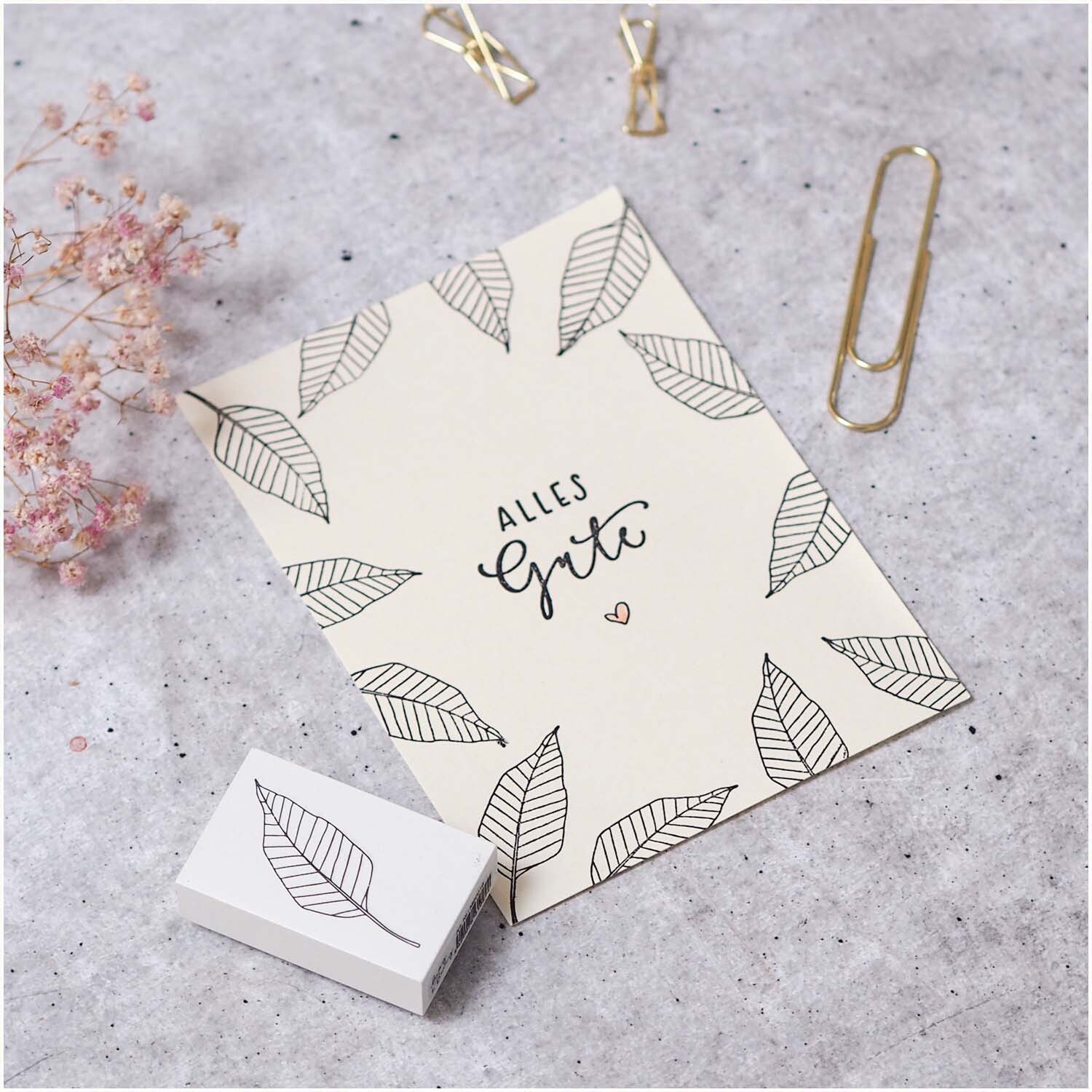 Stempel Blatt stilisiert weiß 35x55mm auf einer Karte mit Blattmuster und "Alles Gute" Text.