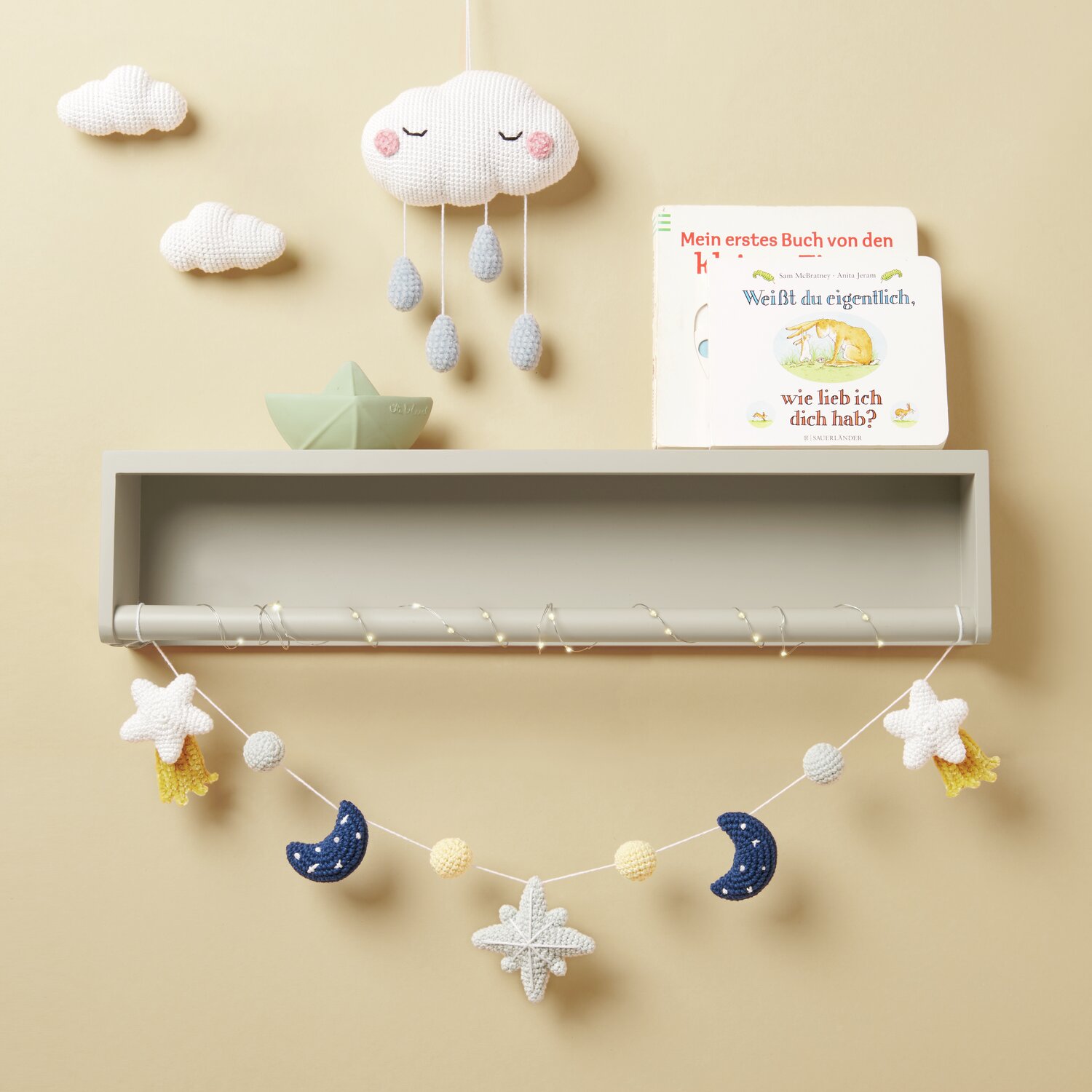 Ricorumi Glow In The Dark: Kinderzimmerdeko mit Wolken-Mobile und Buch auf grauem Regal.