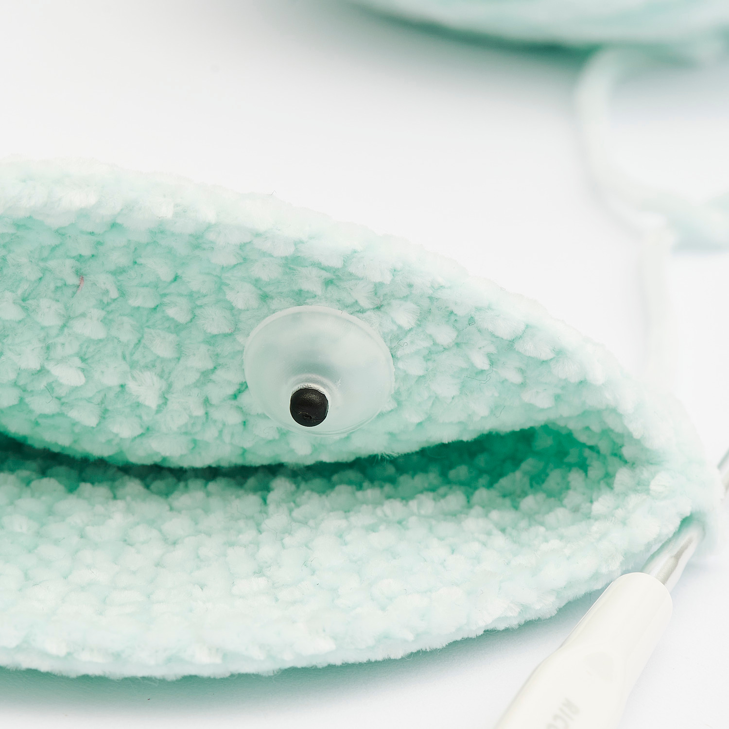 Sicherheitsaugen-Set für Kuscheltiere, 3 Paar 12mm, zeigt ein Auge auf weichem, mintgrünem Stoff. Ideal für DIY-Projekte.
