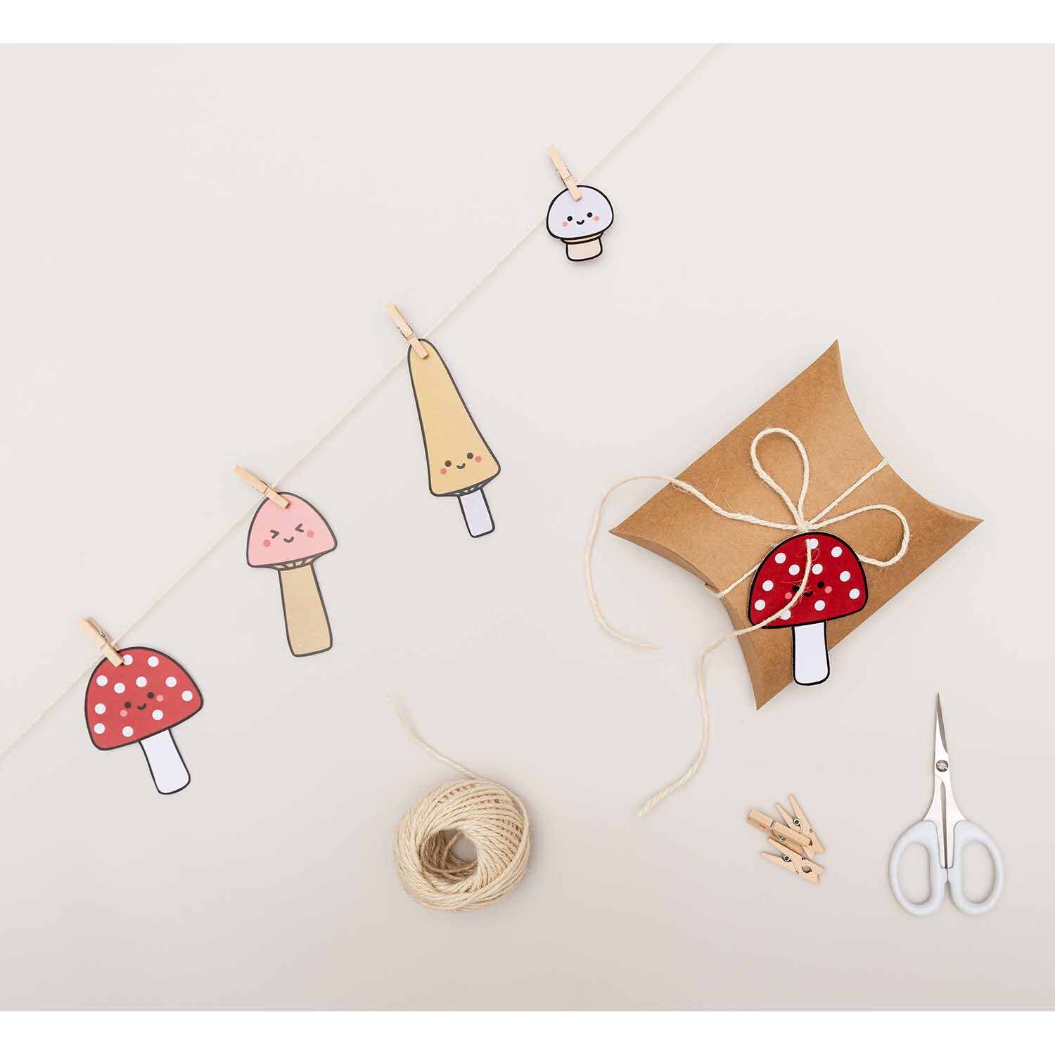 Paper Poetry Papieranhänger Kawaii-Pilze 8 Stück: Mehrfarbige Pilzanhänger an einer Schnur, dekorativ mit Schere und Geschenkbox arrangiert.