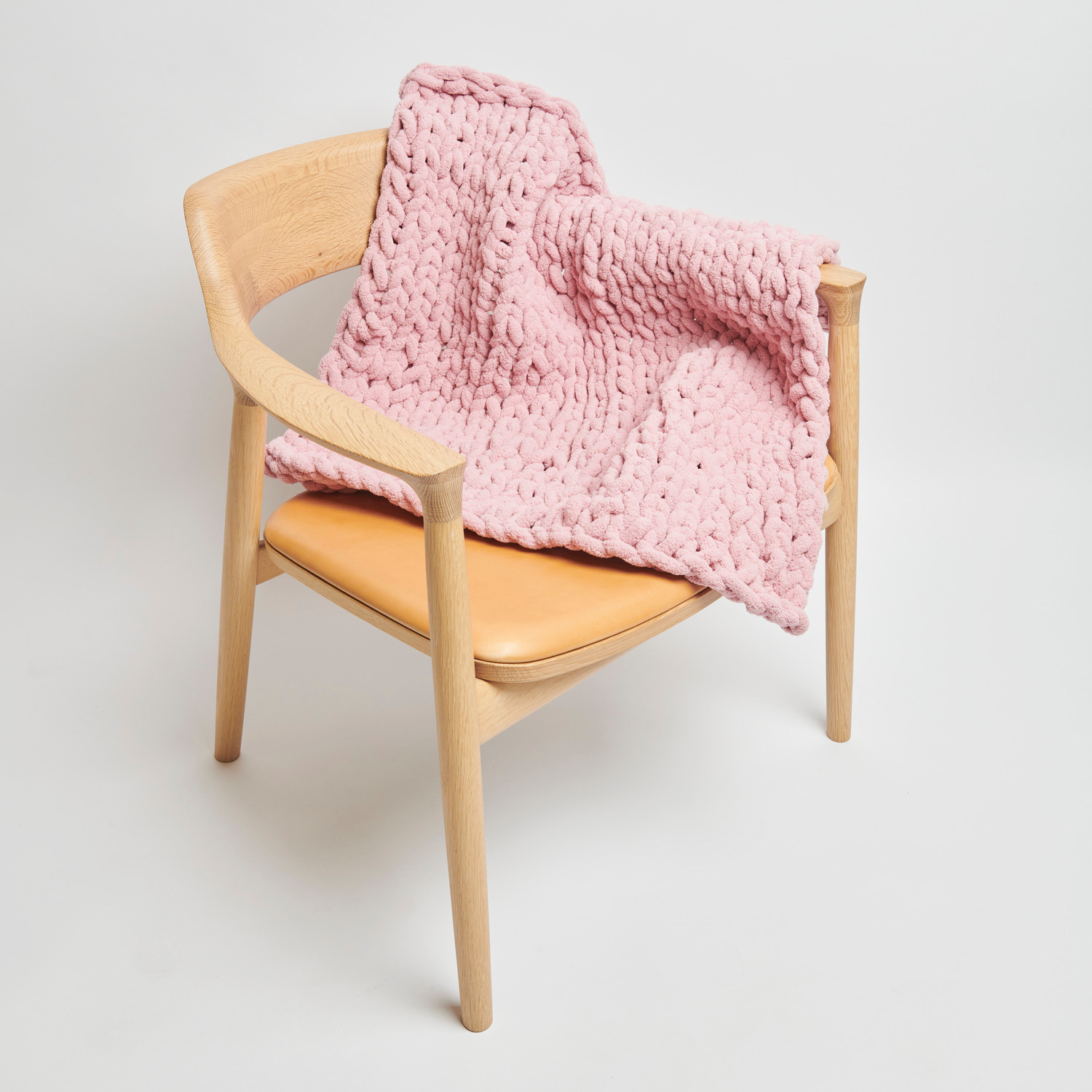 Chenillove Super Big: Weiche, fliederfarbene Decke von Rico Design auf einem Holzstuhl drapiert.
