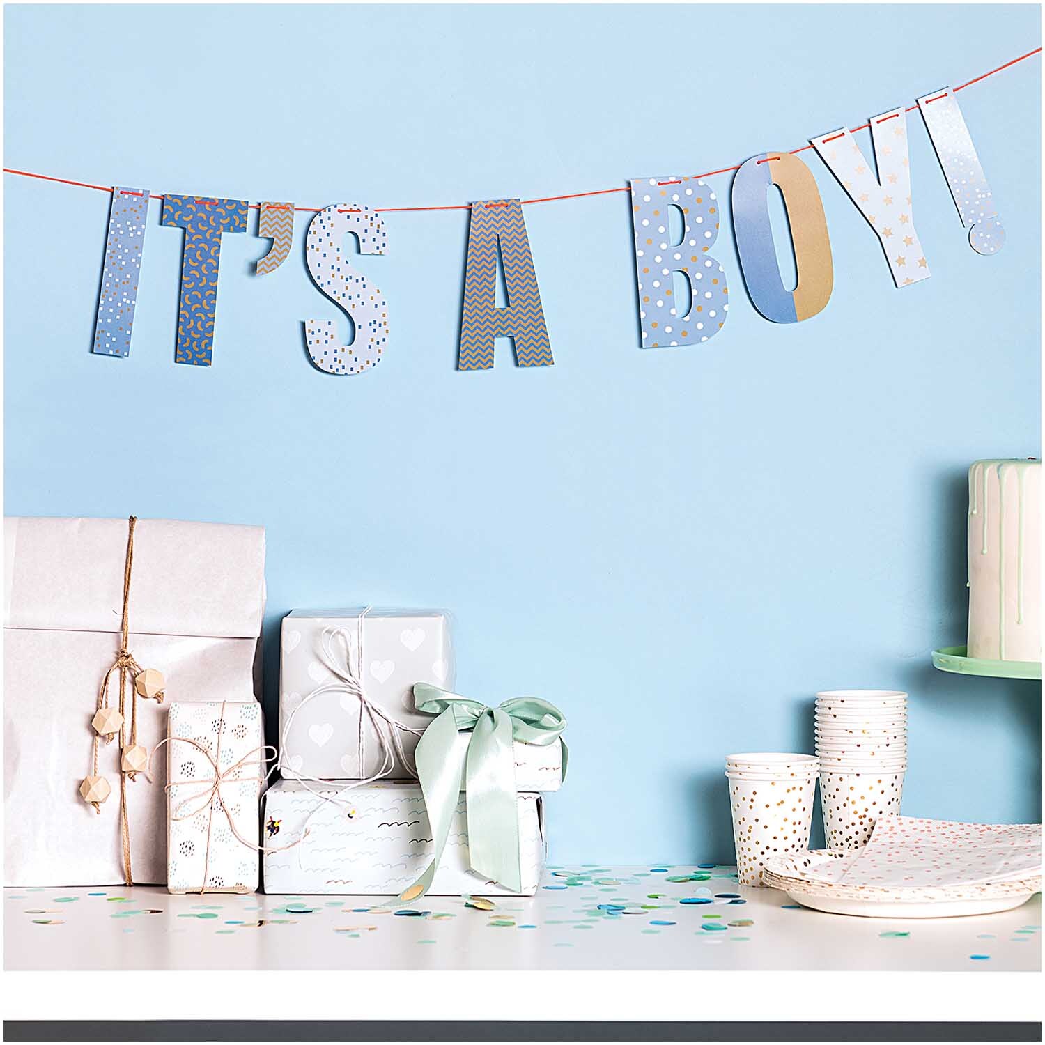 Girlande "It's a boy" 3m von Rico Design über einem Tisch mit Geschenken und Partygeschirr.