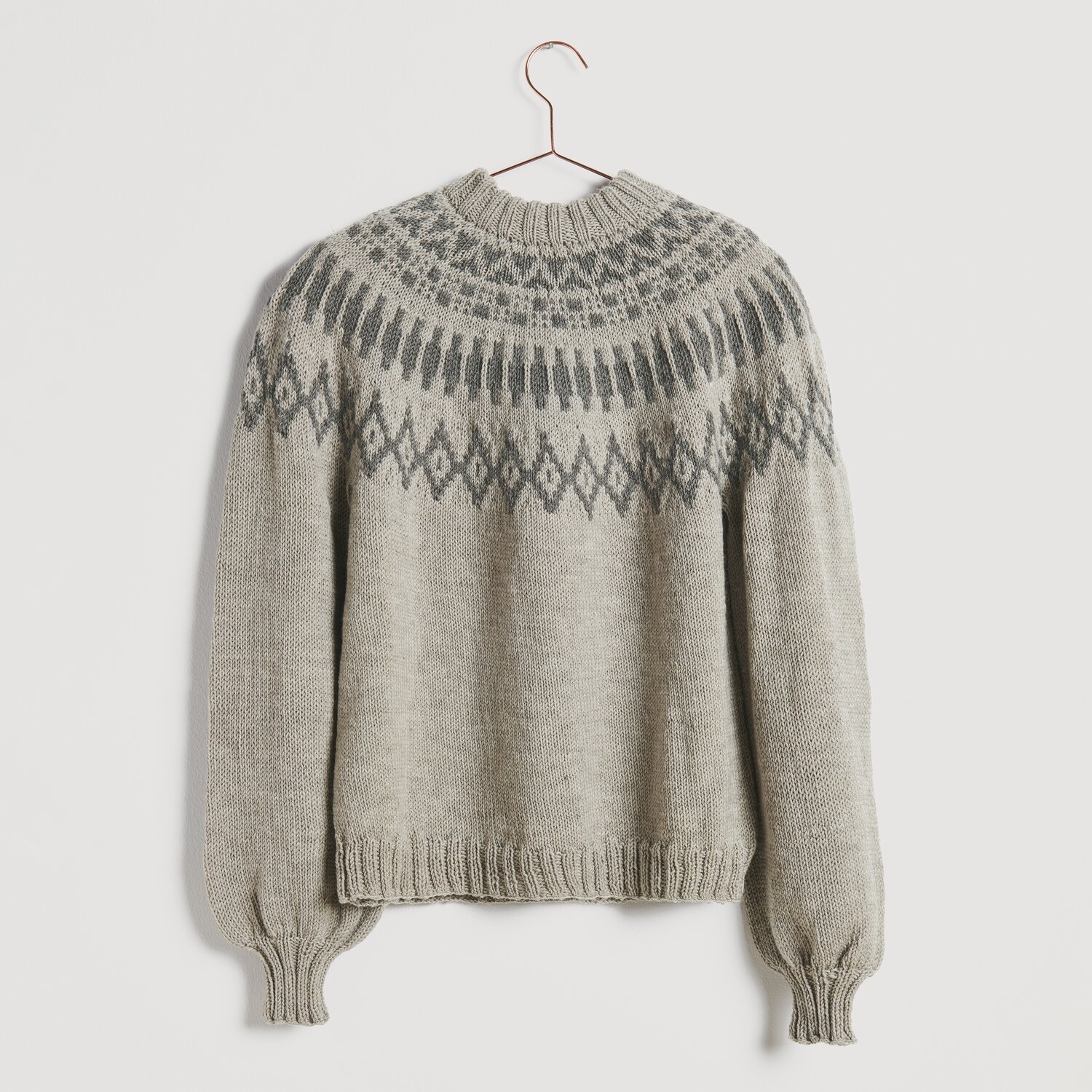 Strickset Pullover Modell 10: Grauer Pullover mit nordischem Muster, hängend an einem Kleiderbügel.