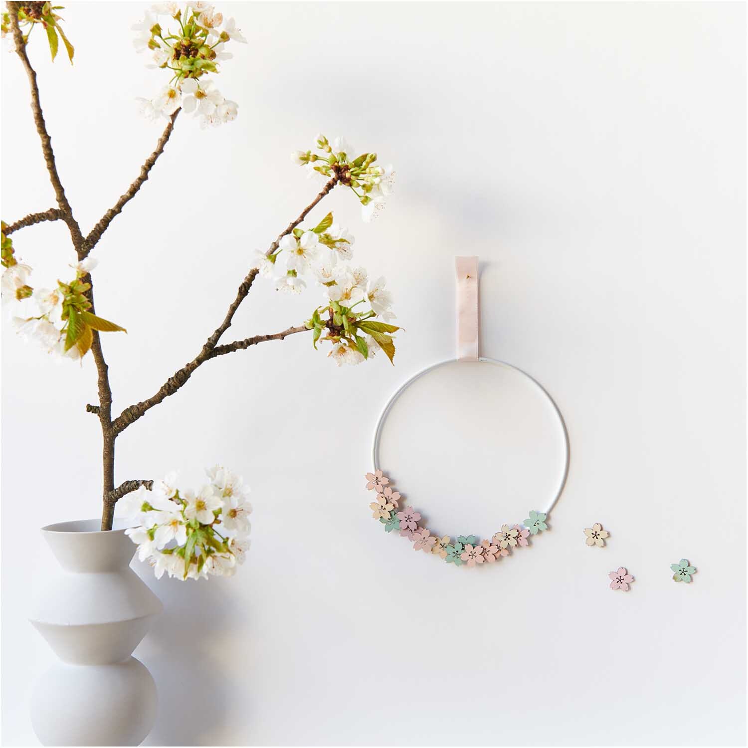 Holzstreu Blüte pastell Mix 48 Stück: Dekorativer Kranz mit zarten Blüten in Pastellfarben an weißer Wand.