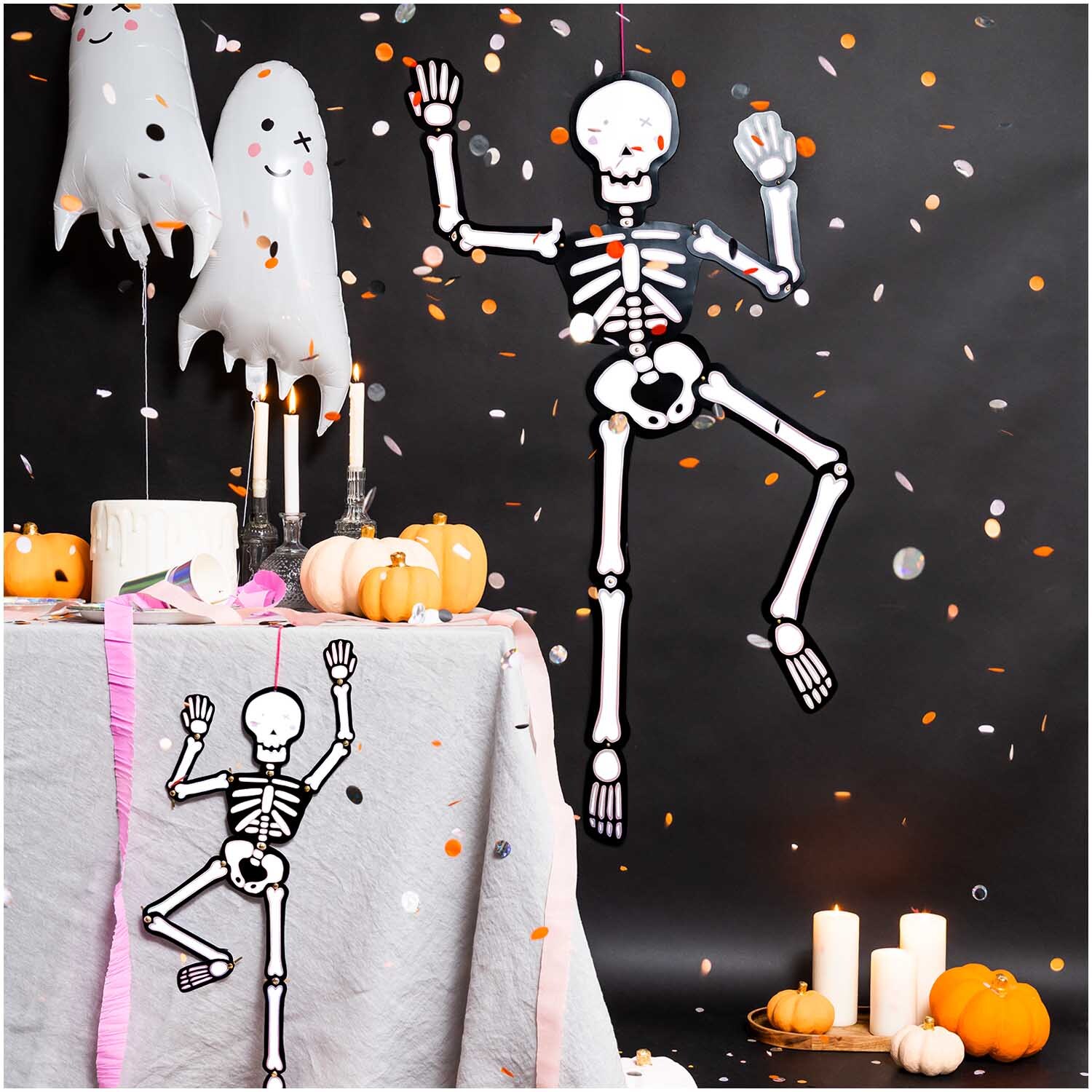 Paper Poetry Hänge-Skelett groß 32x140cm von Rico Design tanzt fröhlich inmitten von Halloween-Dekorationen mit Kürbissen und Geistern.