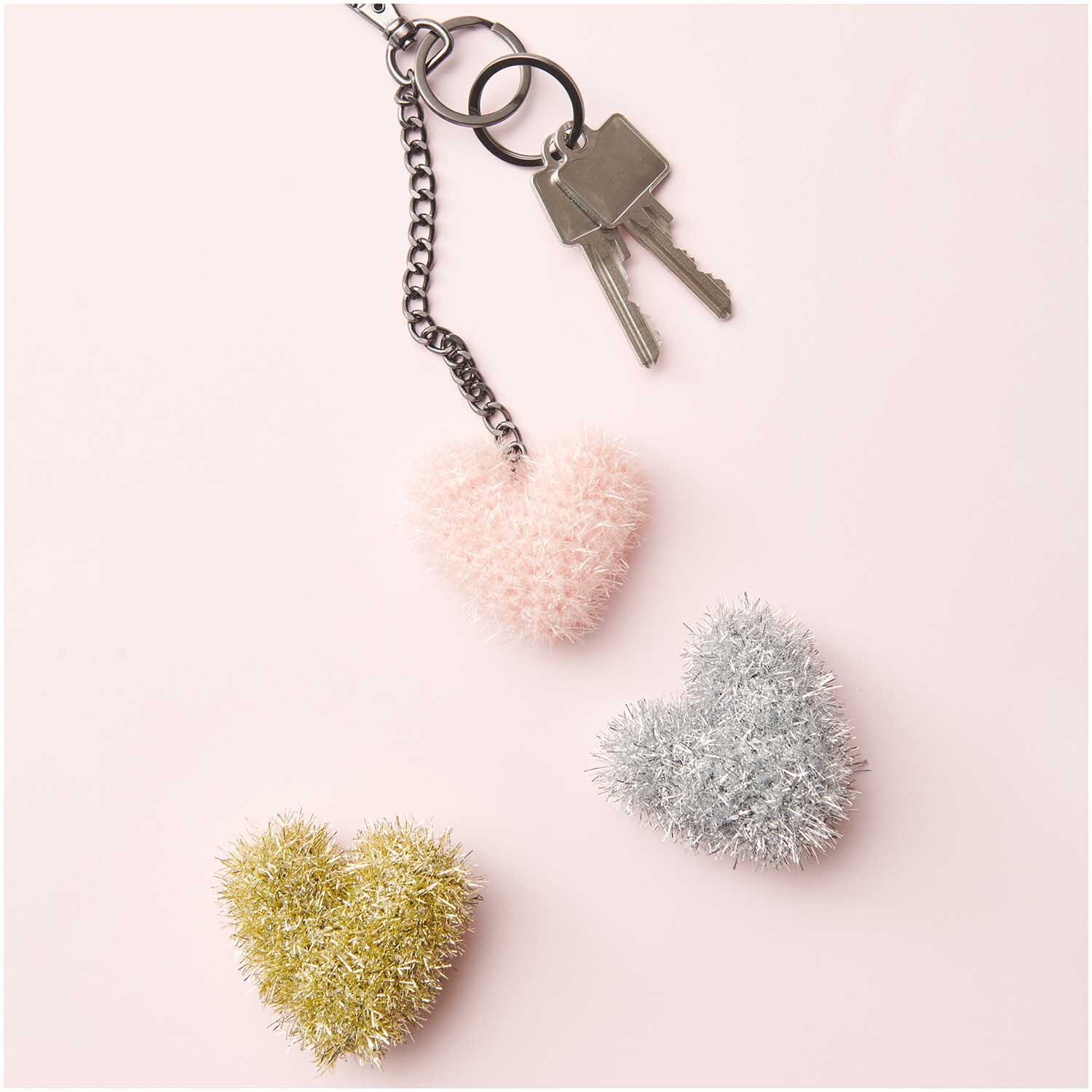 Creative Bubble: Flauschige Herzanhänger in Rosa, Gold und Silber von Rico Design auf rosa Hintergrund.