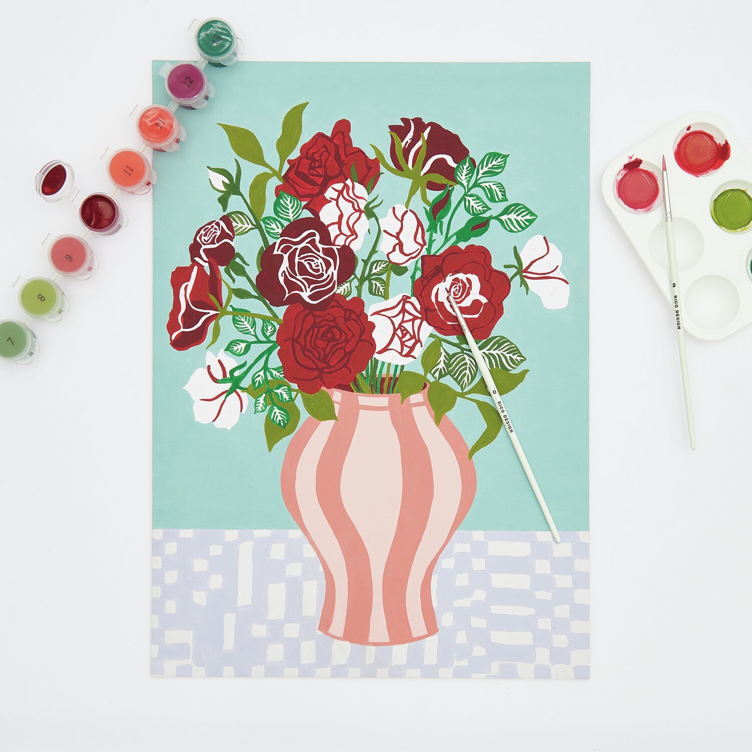 Malen nach Zahlen Rote Rosen: Ein Bild mit roten und weißen Rosen in einer Vase, umgeben von Farbtöpfen und Pinseln.