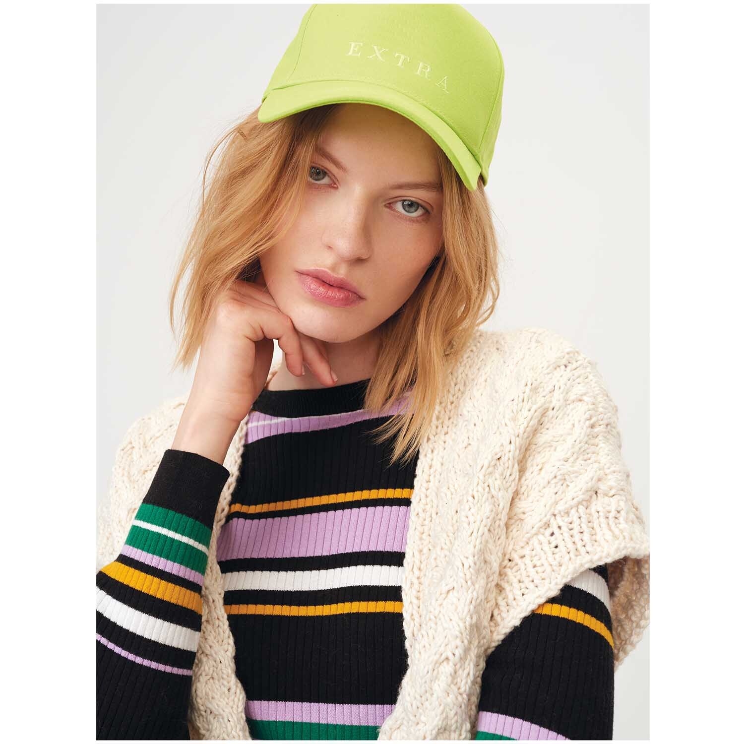 Creative So Cool + So Soft Cotton chunky: Frau mit cremefarbenem Strickschal und gestreiftem Pullover, trägt eine grüne Kappe.