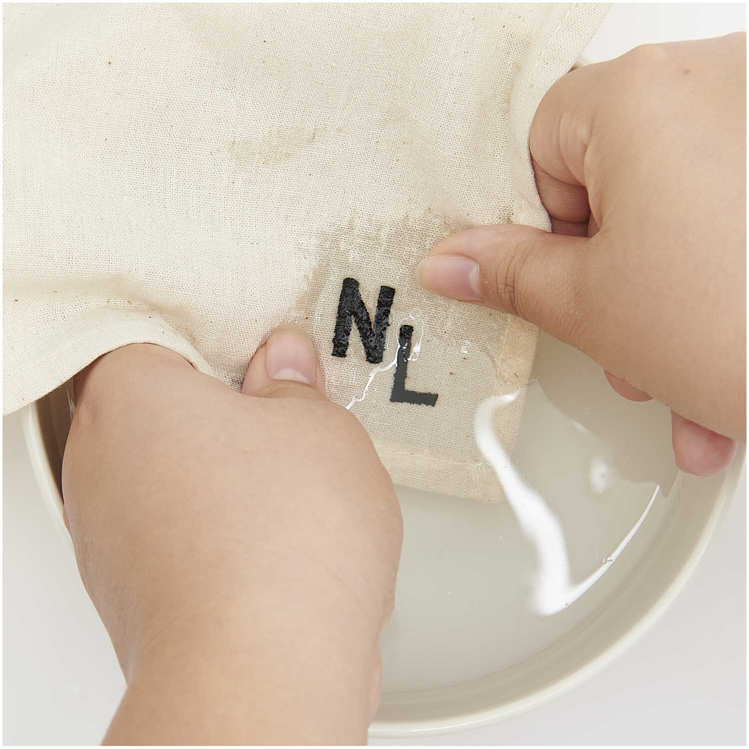 Stick and Stitch Stickpackung Alphabet zeigt Hände beim Sticken von Buchstaben auf Stoff.