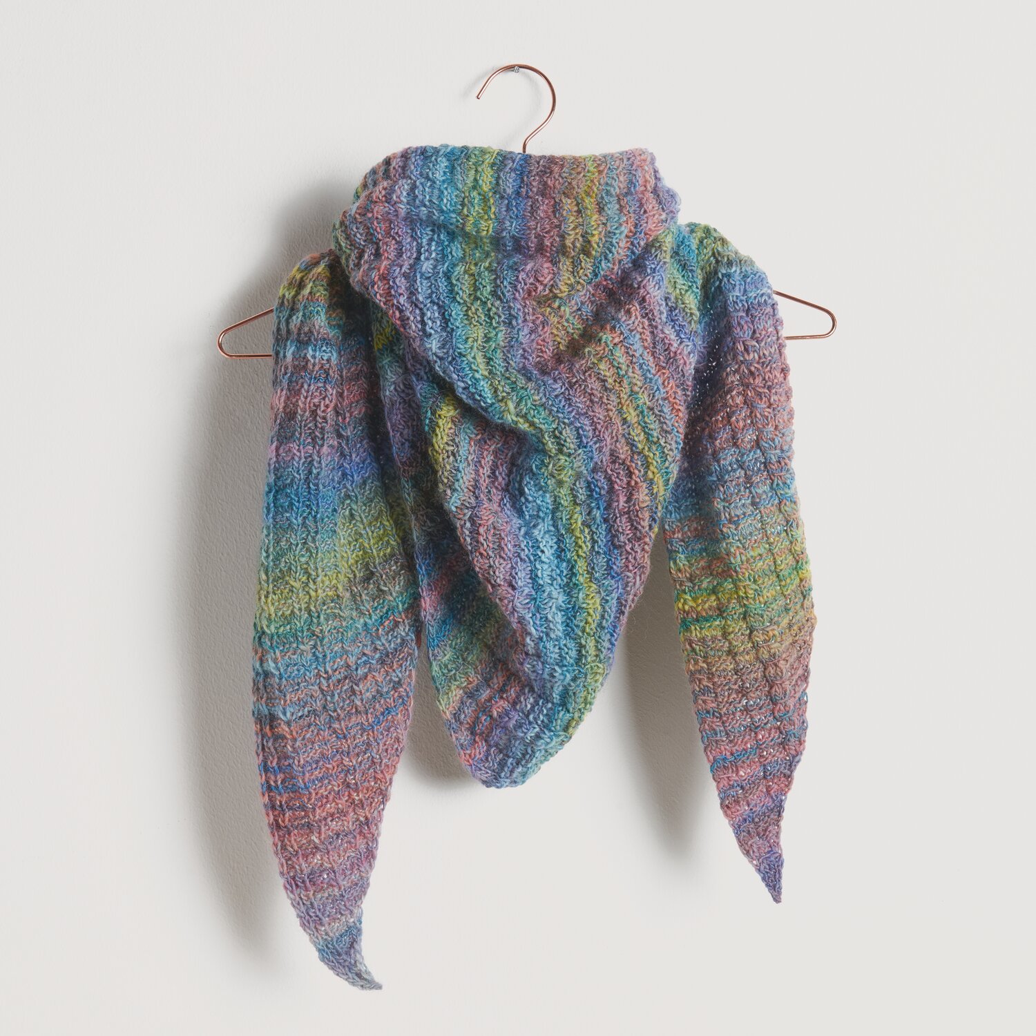 Strickset Dreieckstuch Modell 23: Buntes, handgestricktes Tuch aus Die Neue Masche No. 10, auf einem Kleiderbügel präsentiert.