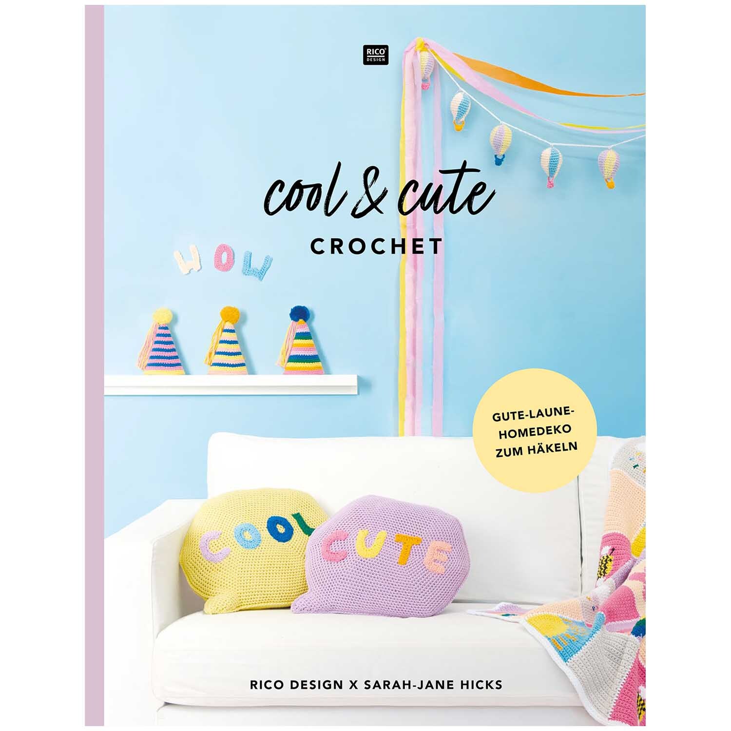 Cool & Cute Crochet: Bunte Kissen und Dekorationen auf einem weißen Sofa vor blauer Wand.
