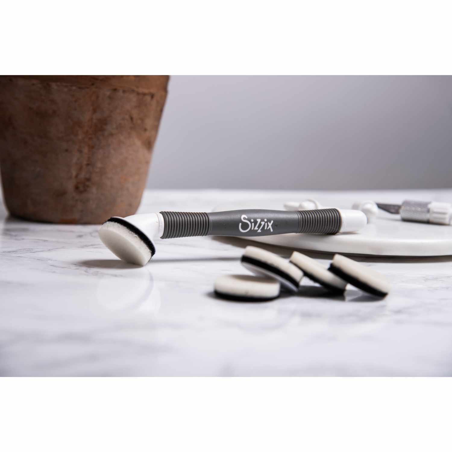 Multi-Tool Accessory Blending Tool von Sizzix auf einem Marmortisch mit mehreren Schwämmen. Ideal für präzises Mischen und Bastelarbeiten.