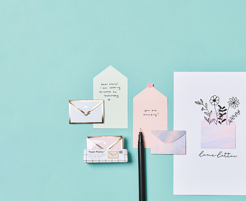 Geöffnete und Geschlossenen Mini-Umschläge mit schwarzem Stift verziert. Flatlay von Produkten.
