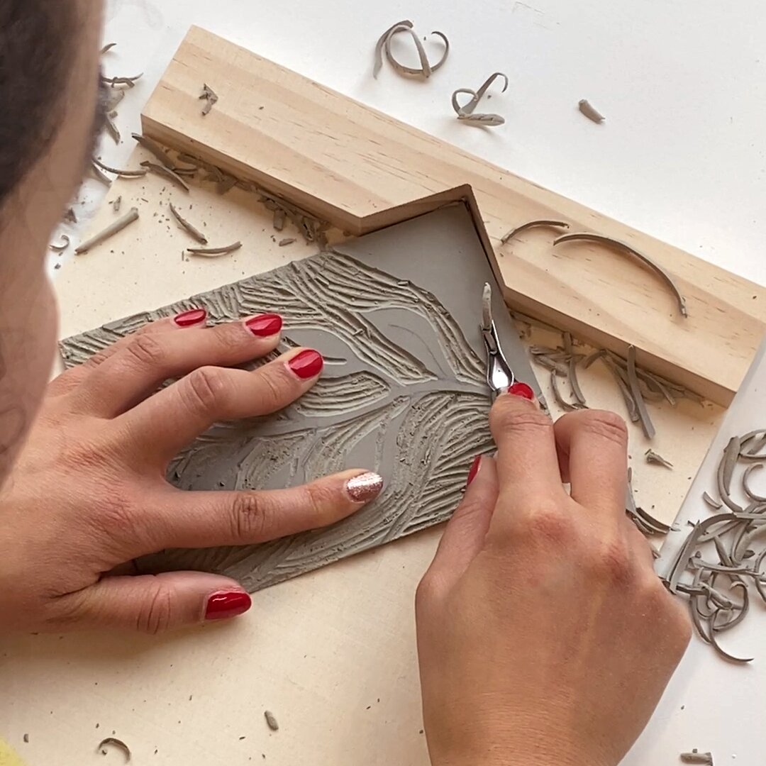 Ricolino Linolschnittwerkzeug zeigt eine Hand beim Schnitzen einer Linolplatte im Schnitzblockhalter von Rico Design, ideal für kreativen 6-teiligen Druckbedarf.