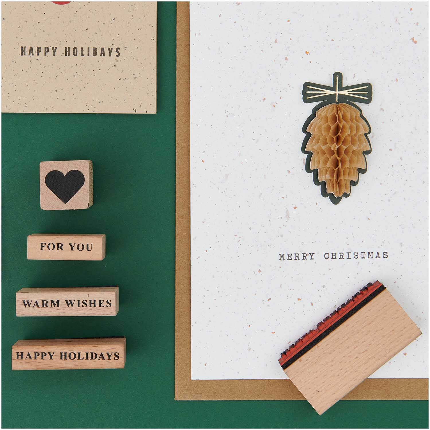 Paper Poetry XL Stempelset Merry Christmas, 27-teilig, zeigt Stempel mit Weihnachtsmotiven und Grußkarten auf grünem Hintergrund.