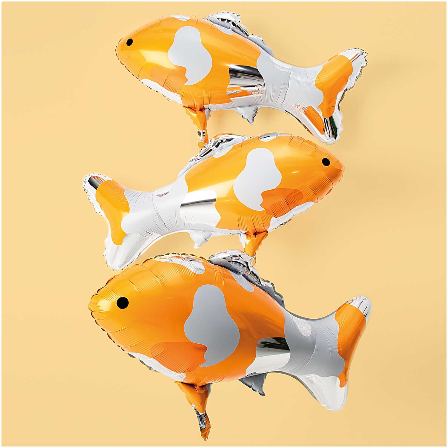 Folienballon Koi silber 86x58,5cm: Drei silberne und orange Koi-Folienballons von Rico Design auf beigem Hintergrund.
