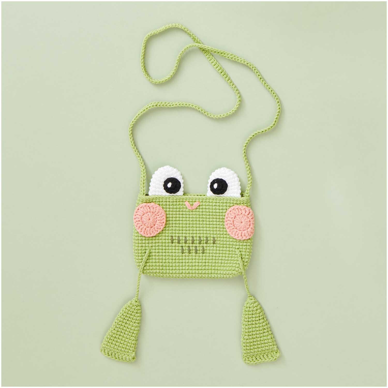 Creative Ricorumi dk: Gehäkelte grüne Froschtasche mit großen Augen und rosa Wangen auf hellem Hintergrund.
