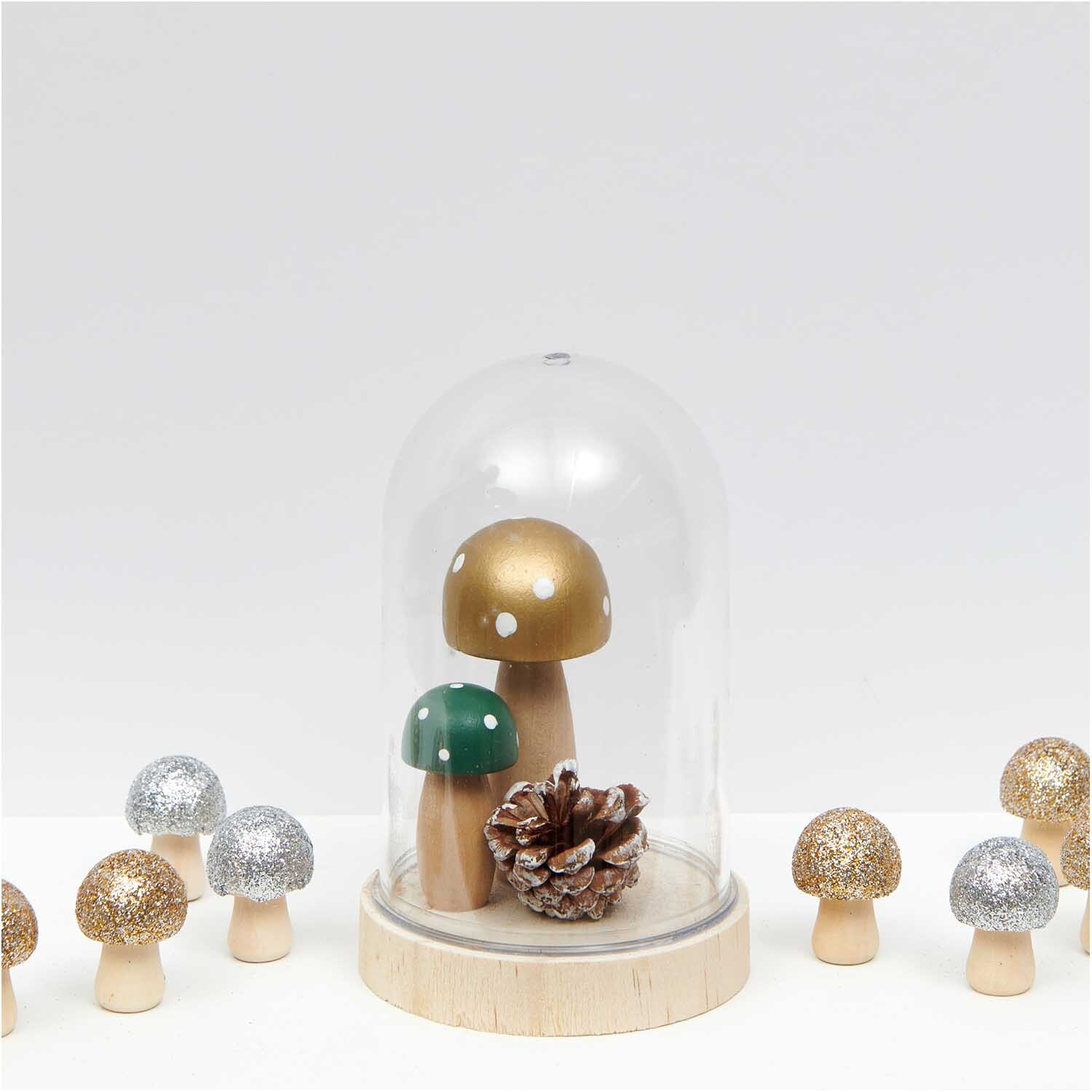 3D-Holzstreu Pilz mit Glitter silber, dekorative Pilze in einer Glaskuppel, umgeben von weiteren glitzernden Pilzen auf weißem Hintergrund.