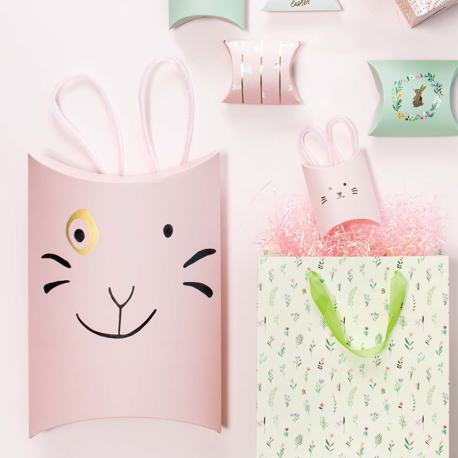 Bastelanleitung Geschenkschachtel Osterhase: Rosa Schachteln mit Hasengesicht und Ohren, dekorativ arrangiert.