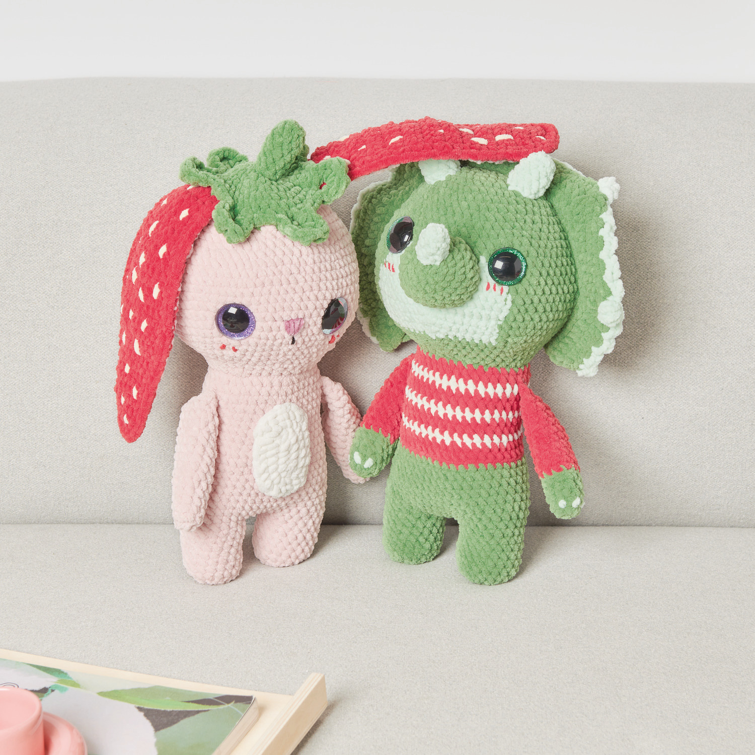 Häkelset Strawberry Bunny Modell 03: Rosa Häschen mit Erdbeerohren, neben grünem Dinosaurier.