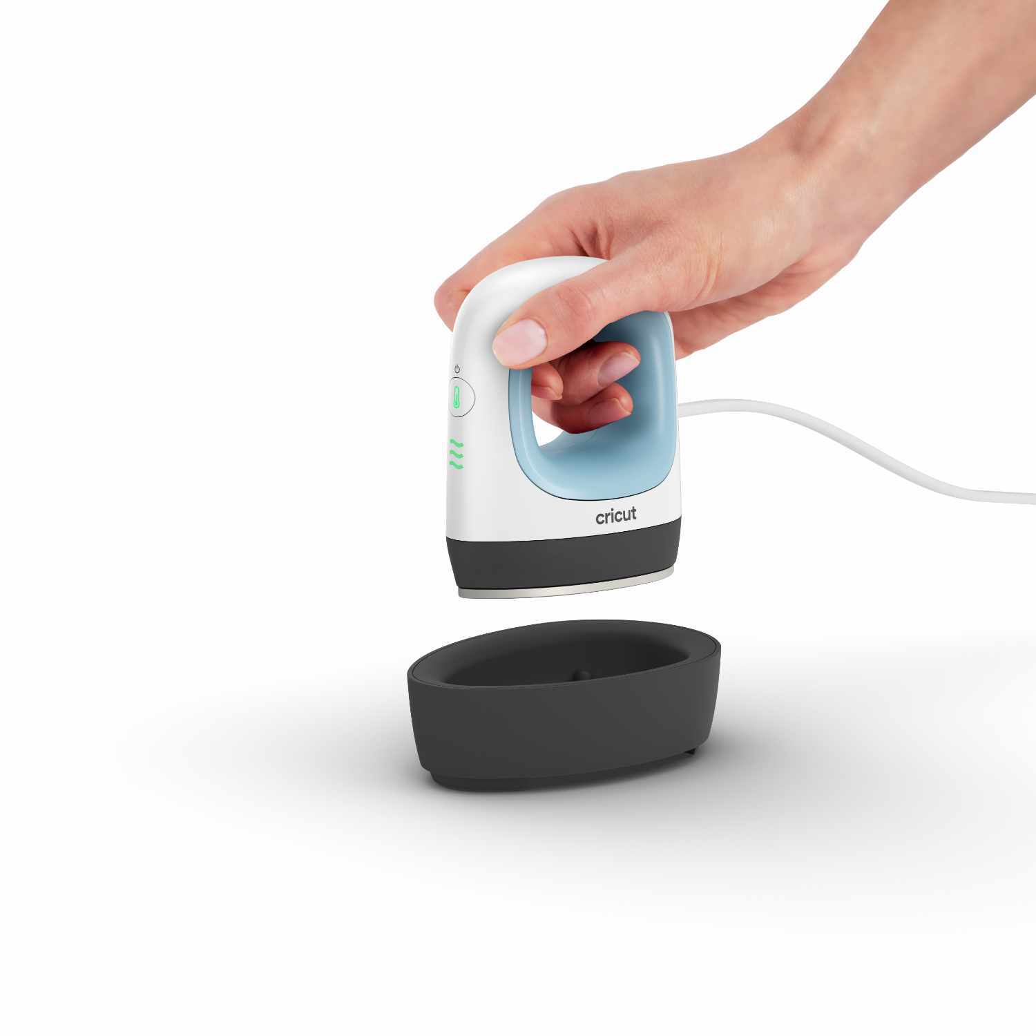 Easypress Mini Zenblue von Cricut in Aktion, gehalten von einer Hand über einer schwarzen Basis. Ideal für präzise Bügelarbeiten.