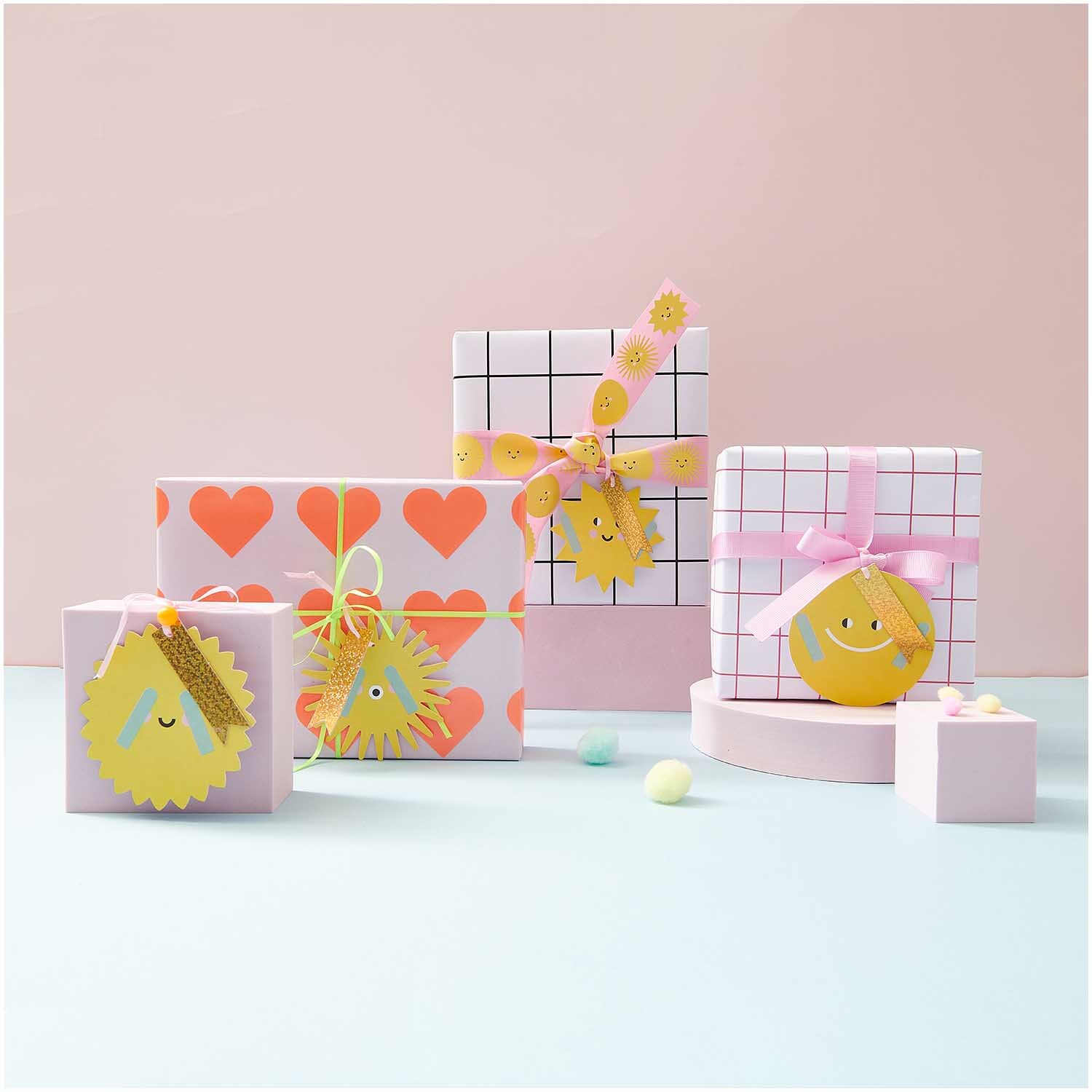 Paper Poetry Geschenkanhänger Sonne 4 Stück: Vier Geschenke mit fröhlichen Sonnenanhängern von Rico Design, dekoriert in Pastelltönen.