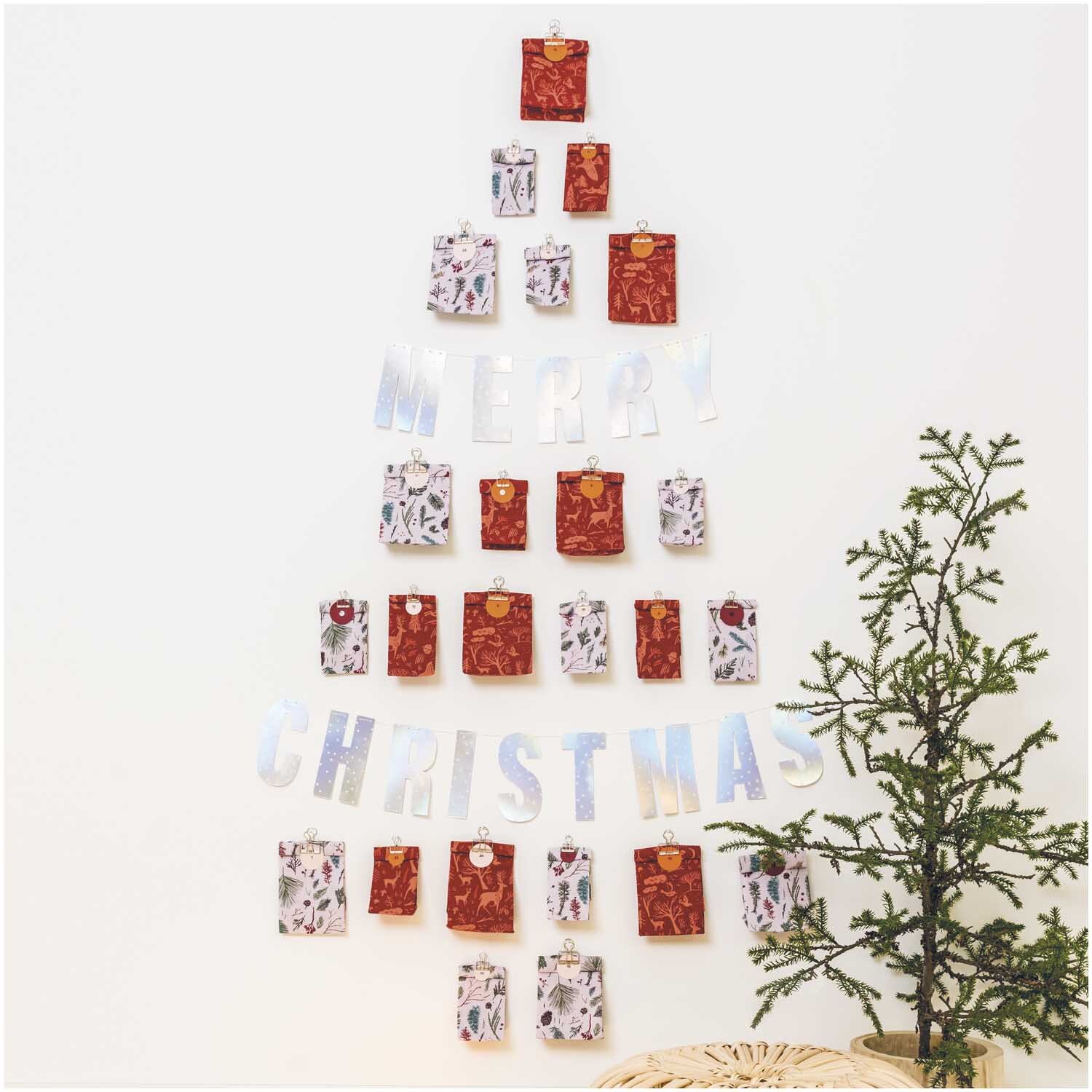 Druckstoff Nostalgic Christmas Zweige rosa 140cm: Adventskalender in Baumform mit Geschenken und Schriftzug "Merry Christmas" an der Wand.