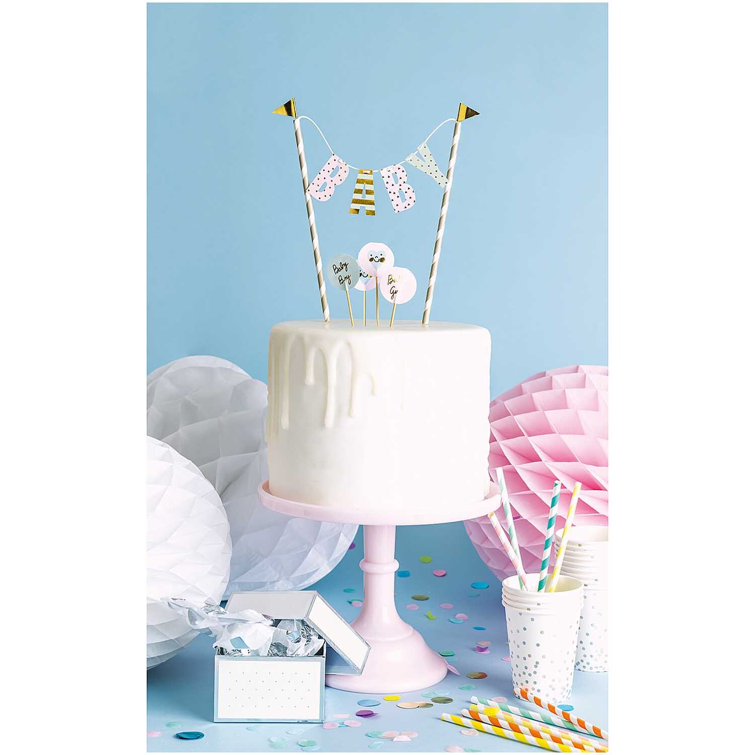 Kuchendekoration Baby: Weißer Kuchen auf rosa Ständer mit bunter Girlande, von Rico Design.