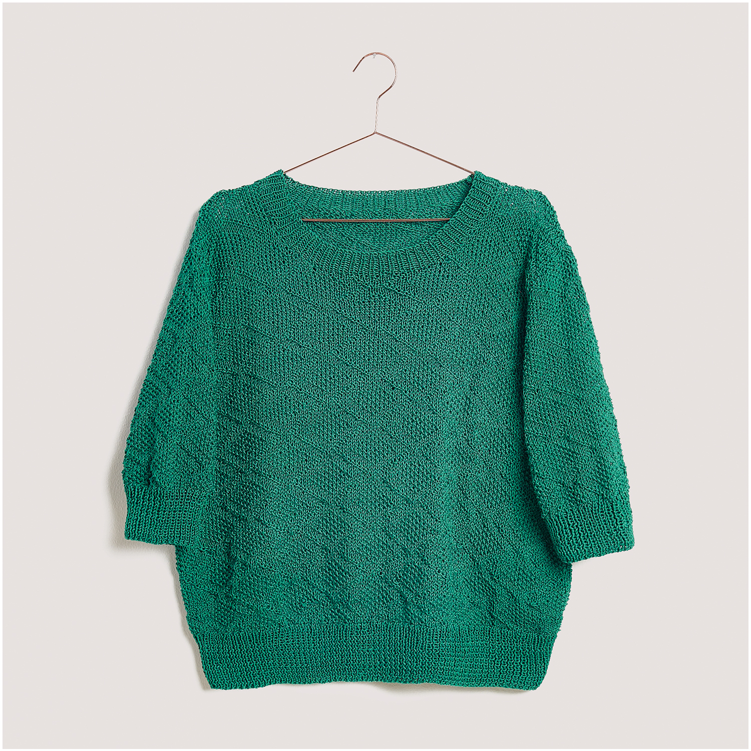 Strickset Shirt Modell 25 aus Lovewool Nr. 18: Grünes Strickshirt mit Dreiviertelärmeln auf einem Kleiderbügel.