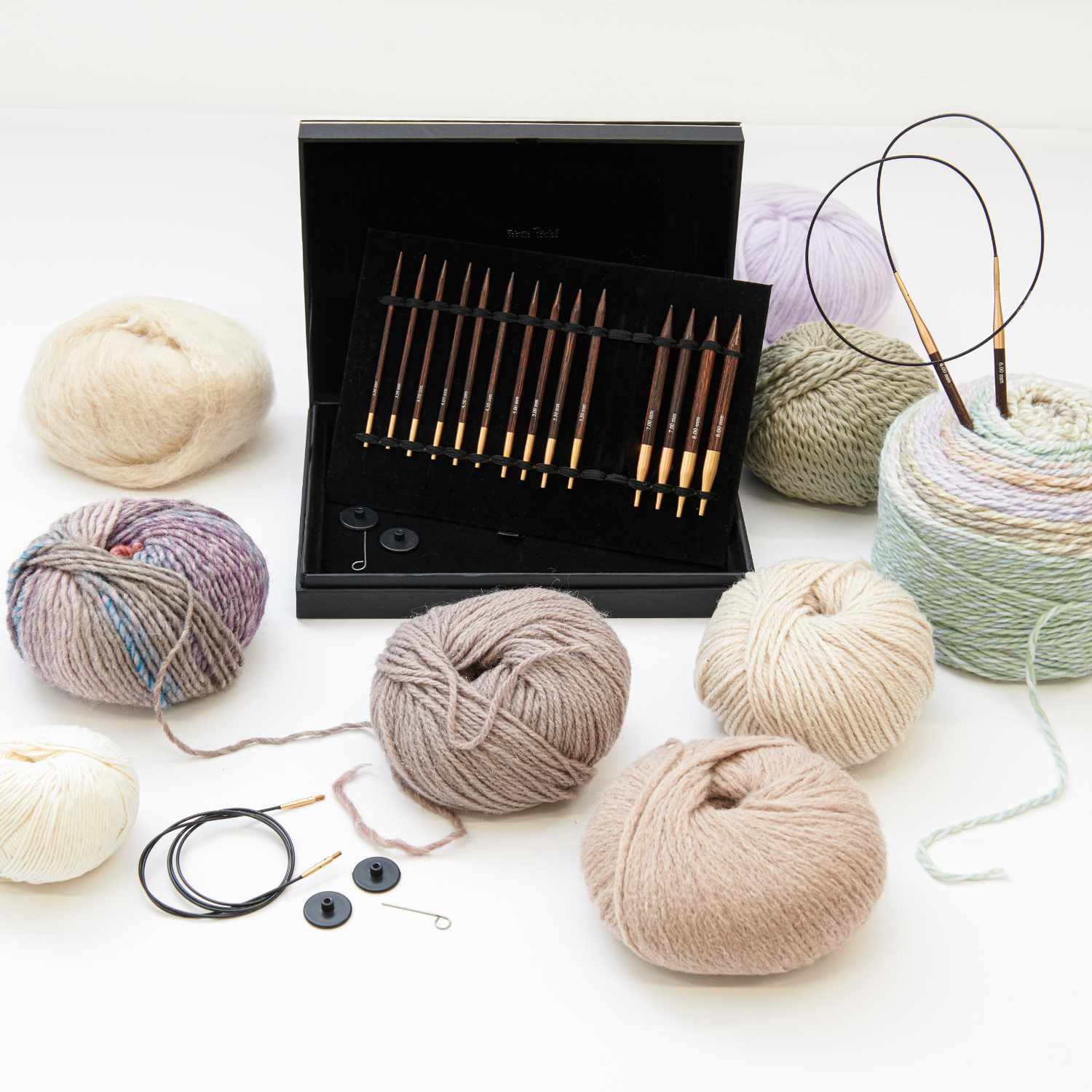 KnitPro Rundstricknadel Set auswechselbar Holz, umgeben von Wollknäueln in verschiedenen Farben, präsentiert in einer eleganten Box.