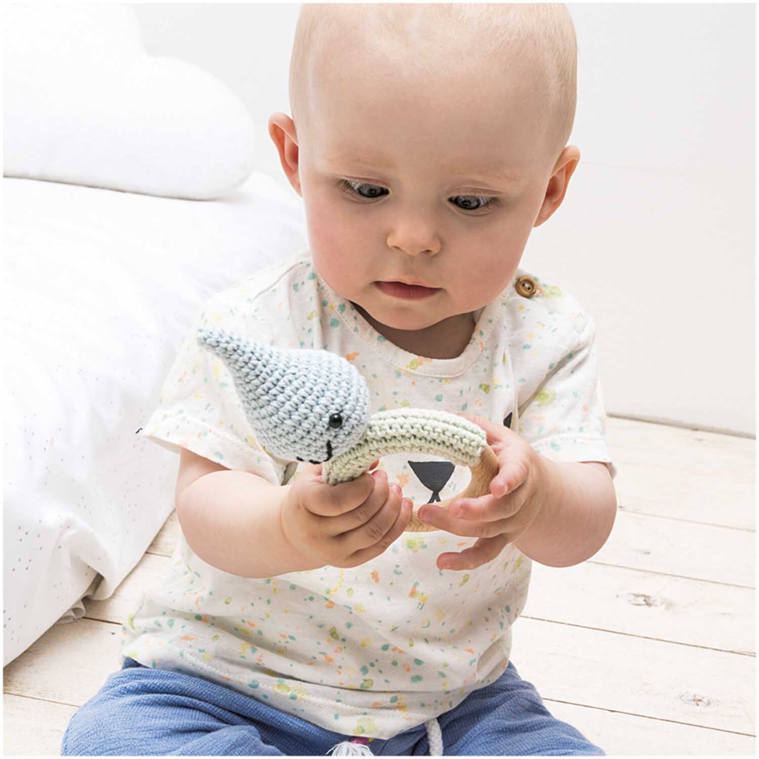 Creative Ricorumi dk: Ein Baby hält ein gehäkeltes Spielzeug. Garn von Rico Design in 25g Knäuel.