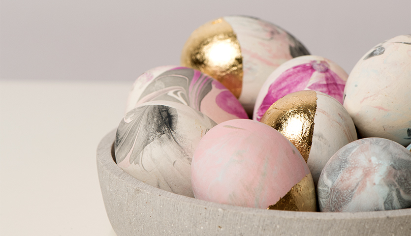 Anleitung Ostereier marmorieren mit Acrylfarben: Bunte, marmorierte Ostereier in einer Schale, verziert mit Goldakzenten.