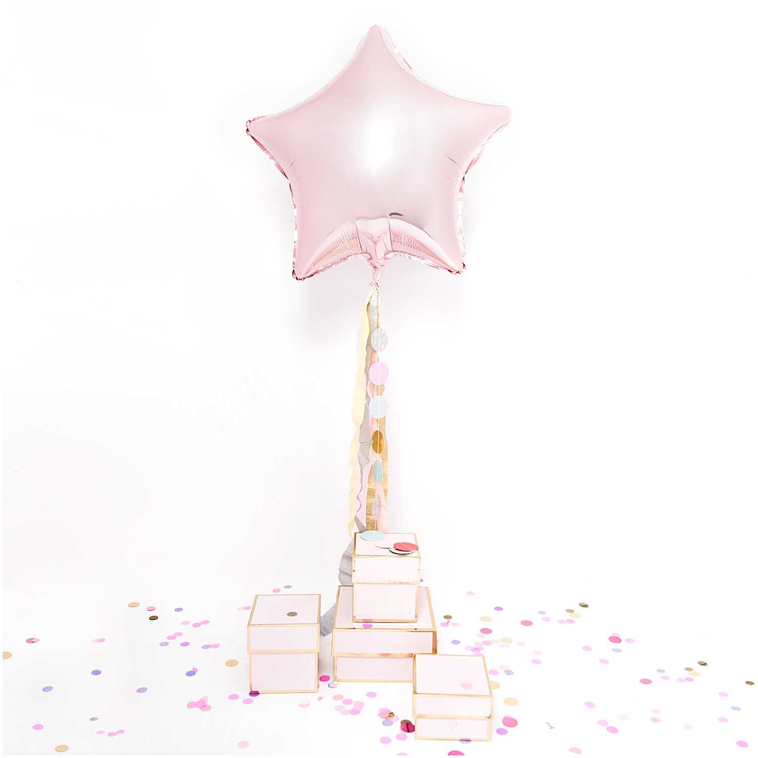 Konfetti pastell Mix 20g von Rico Design, verstreut um rosa Sternballon und Geschenkboxen.