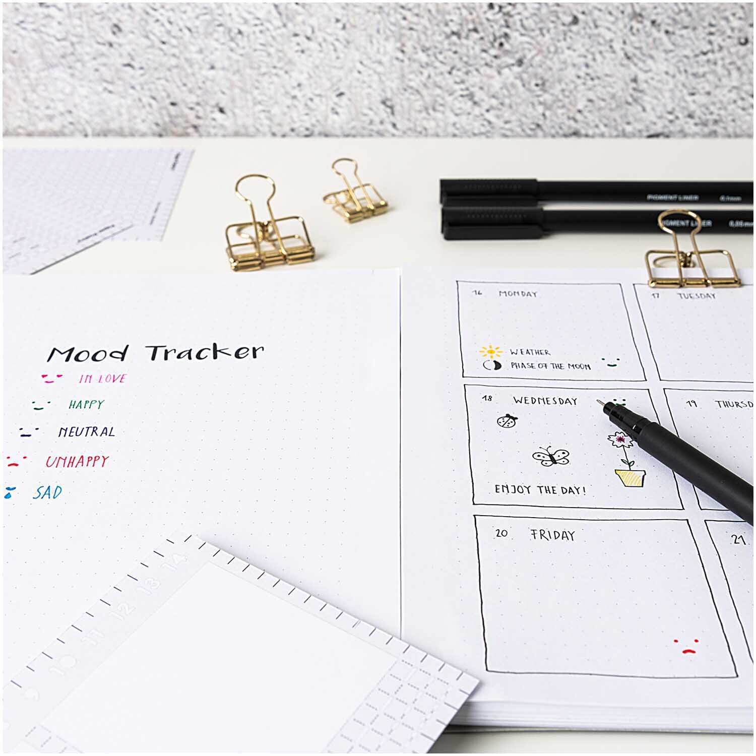 Paper Poetry Bullet Diary Schablone zeigt Mood Tracker und Wochenplaner auf Schreibtisch mit Stiften.